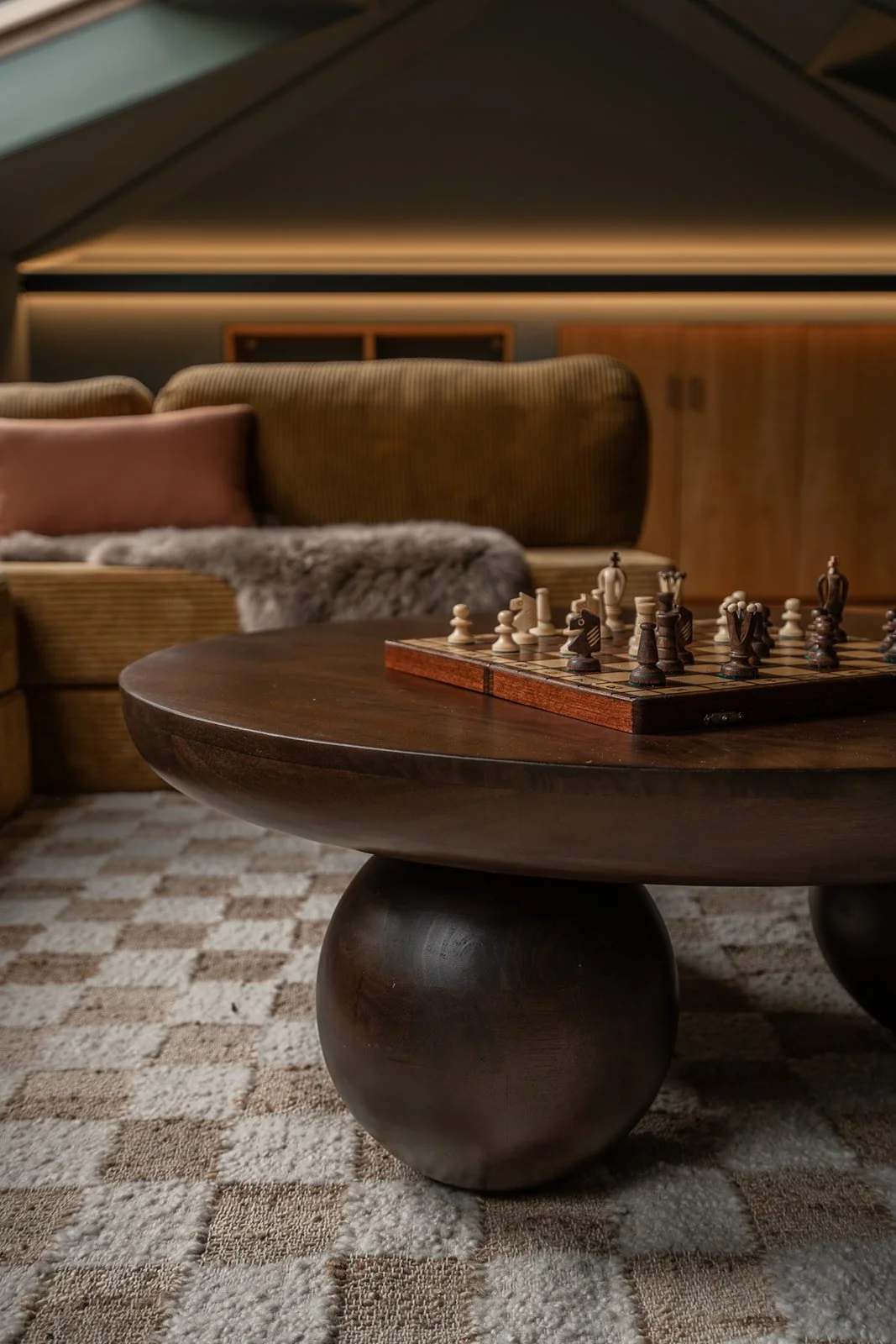 Sculptural dark wood coffee table and chess set in the warm, relaxed home cinema.
