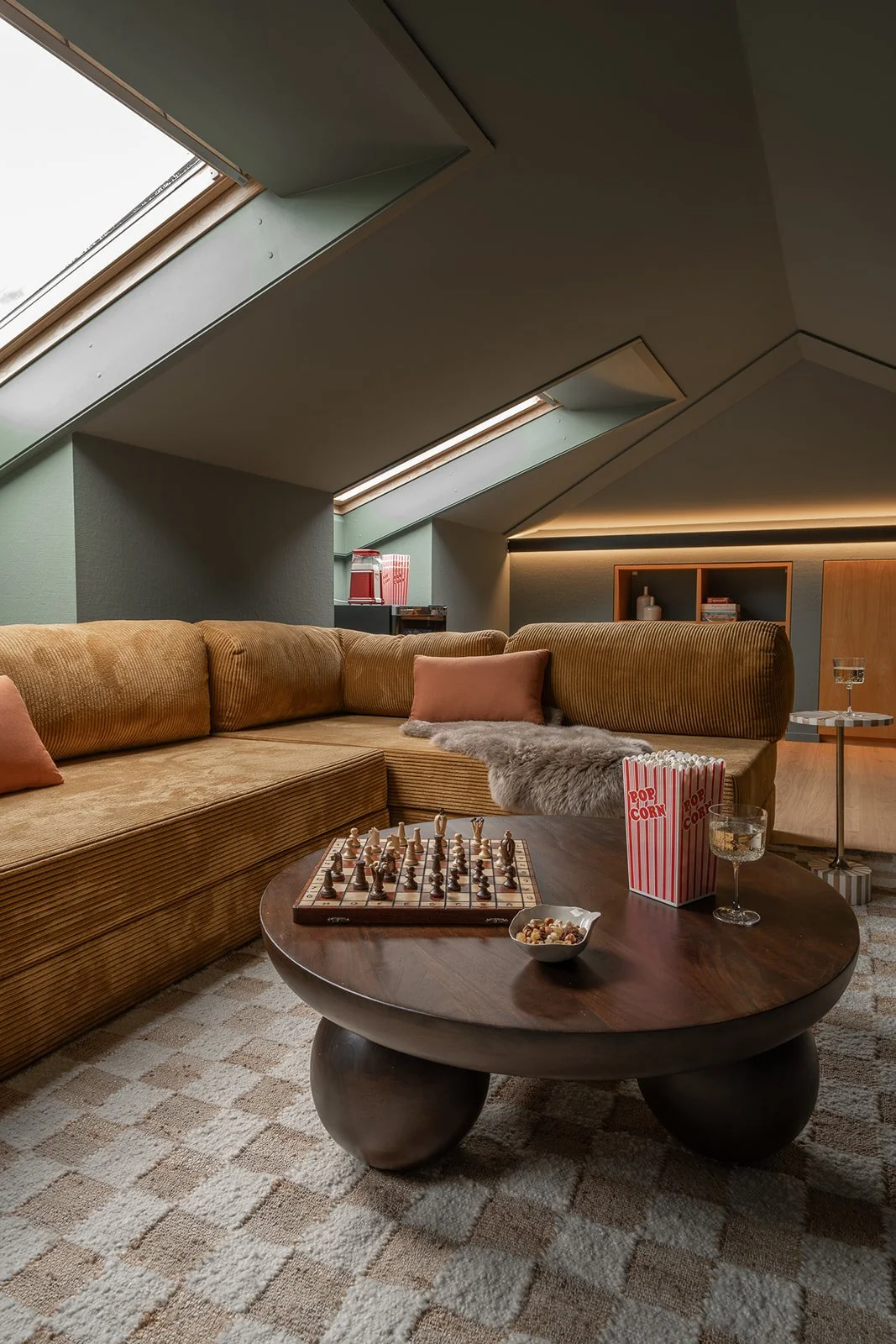 Home cinema seating area with corduroy sectional sofa, patterned rug and warm integrated lighting.