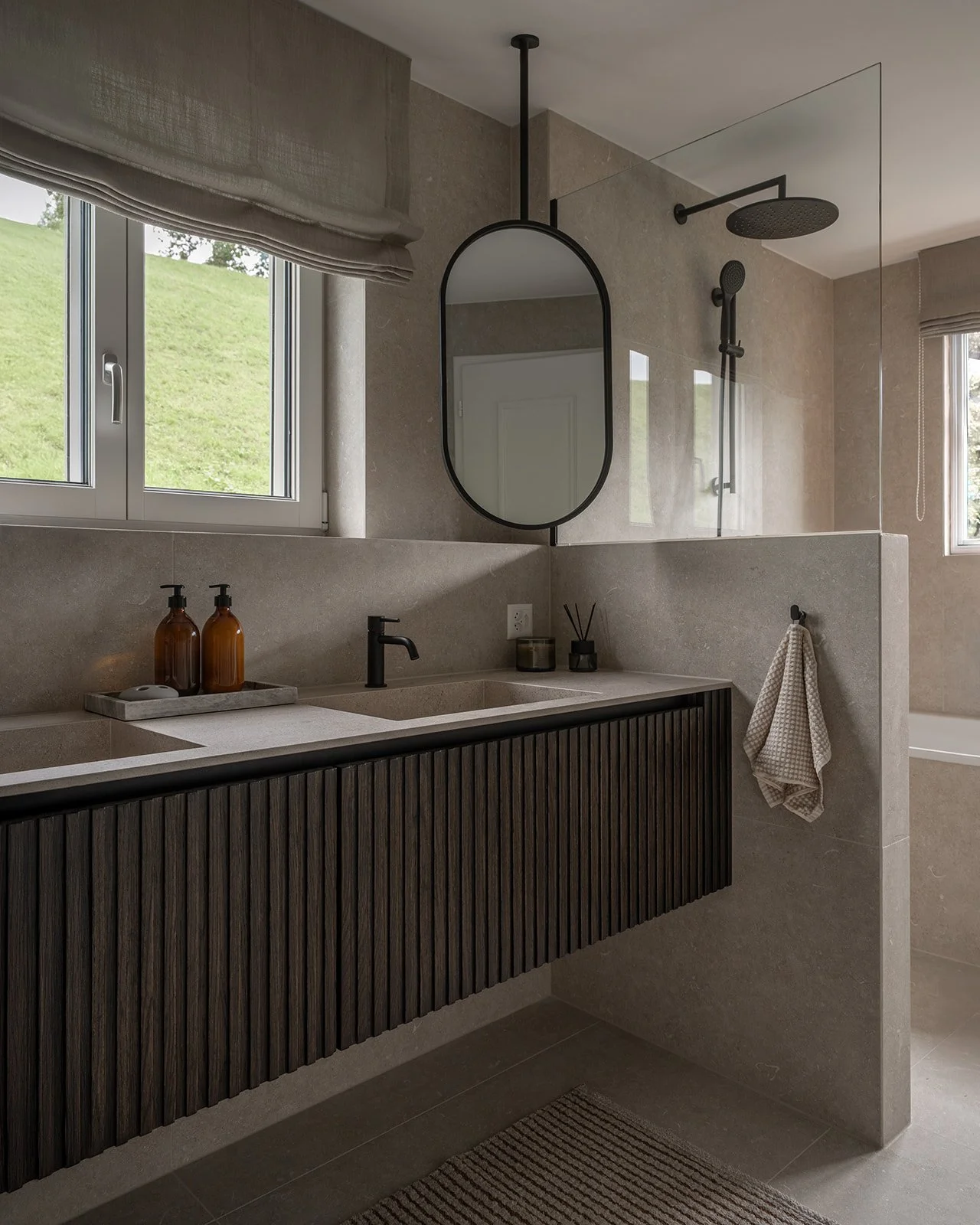 Detail of the dark fluted wood vanity with stone countertop and black fittings.