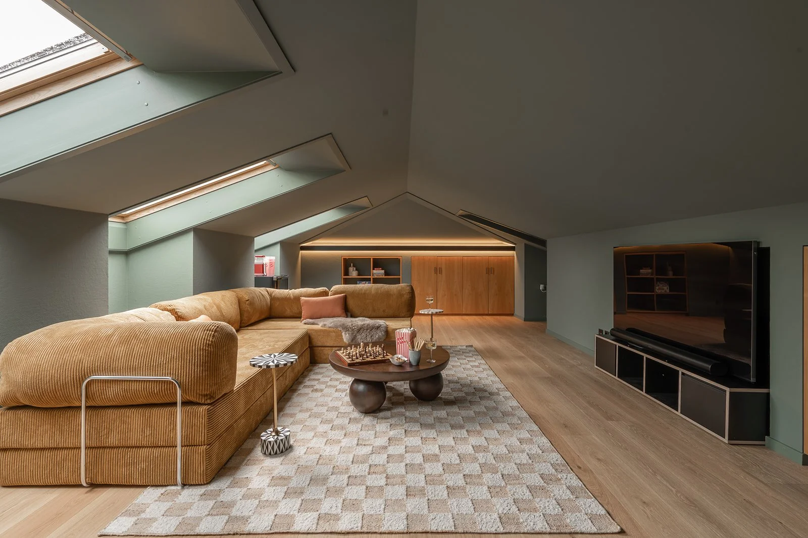 Home cinema with large sectional sofa, skylights and built-in storage at Landhaus Ennetmoos.