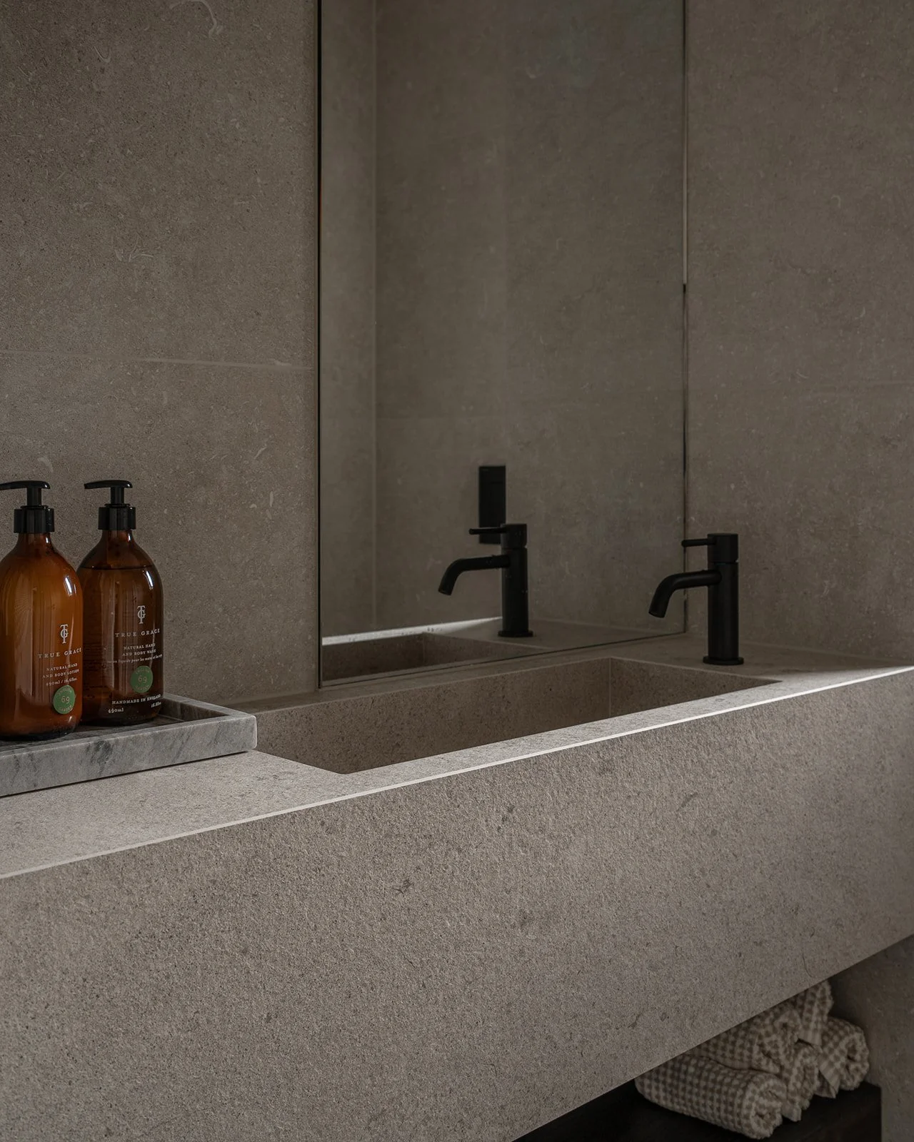 Close-up of the integrated stone basin, black tap and mirror in the main bathroom.