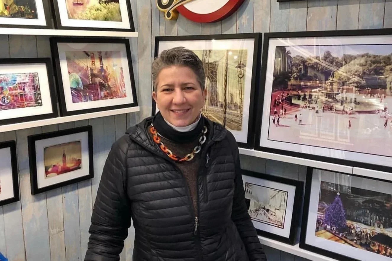 Photographer Tam Benjamin in front of a wall of her framed prints
