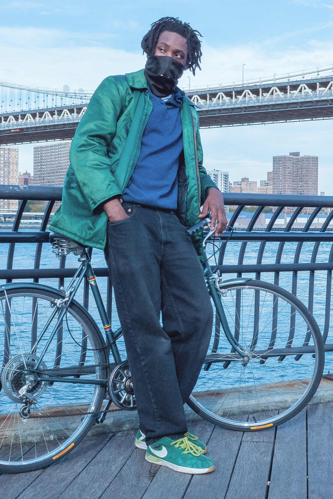 A biker wearing the Mask standing by a bridge