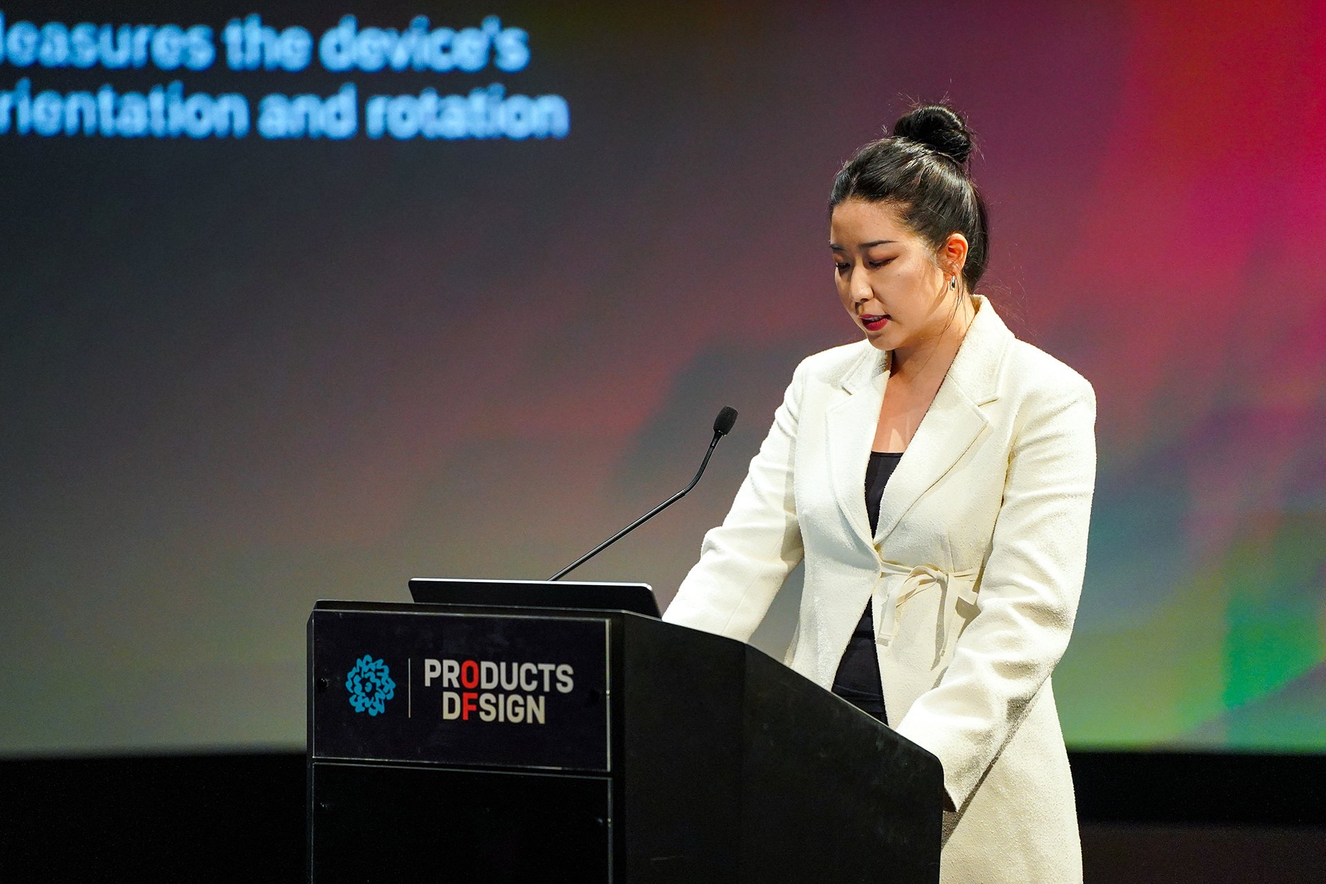  Speaker at podium with screen behind her with text 