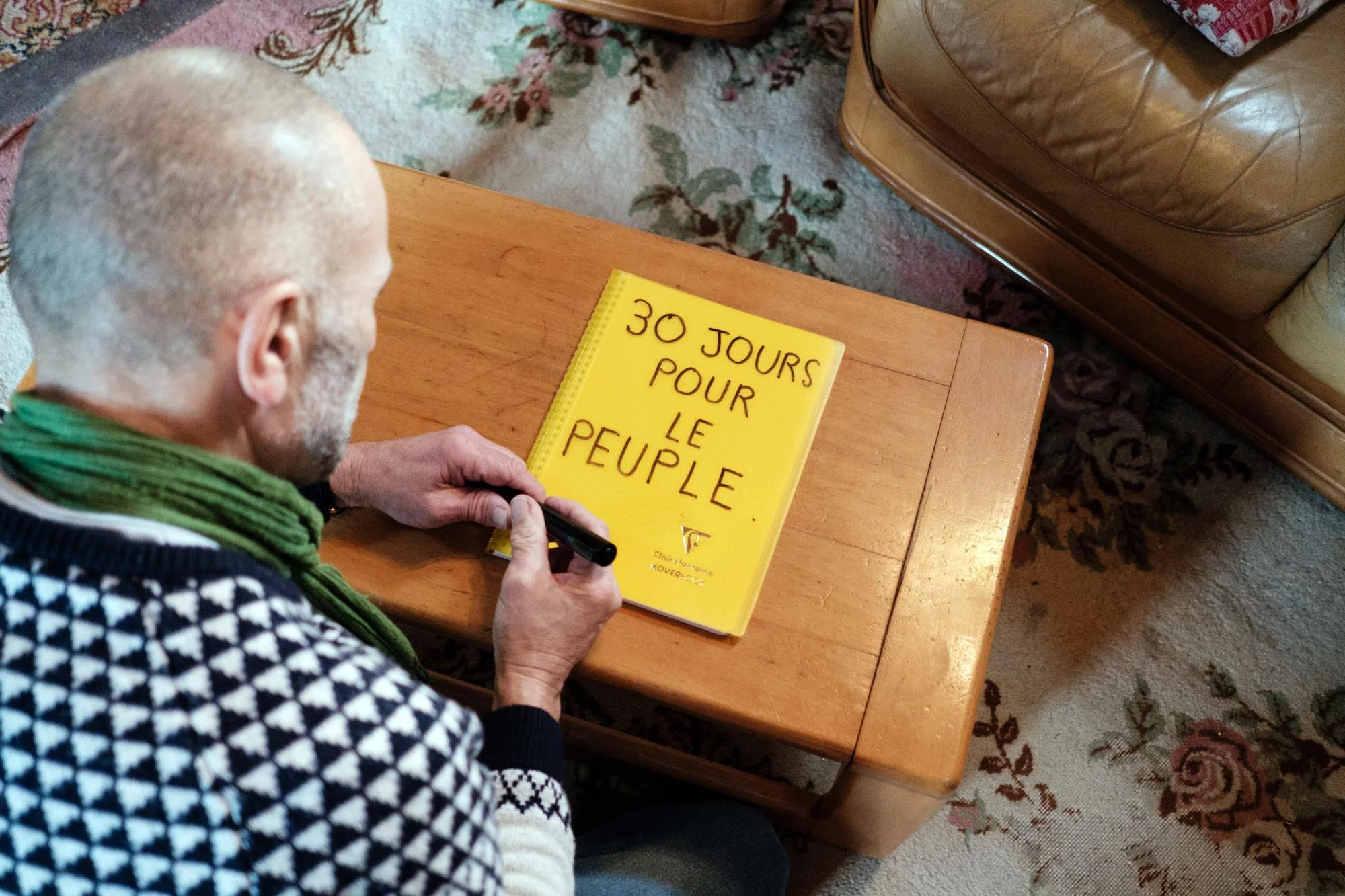  Patrick de Perglas (dit Gepy) écrit sur un cahier le nom de la page Facebook « 30 jours pour le peuple ». Il souhaite écrire tous les messages et les mots de soutien laissés par les personnes rencontrées lors de sa marche vers le palais de l’Elysée 