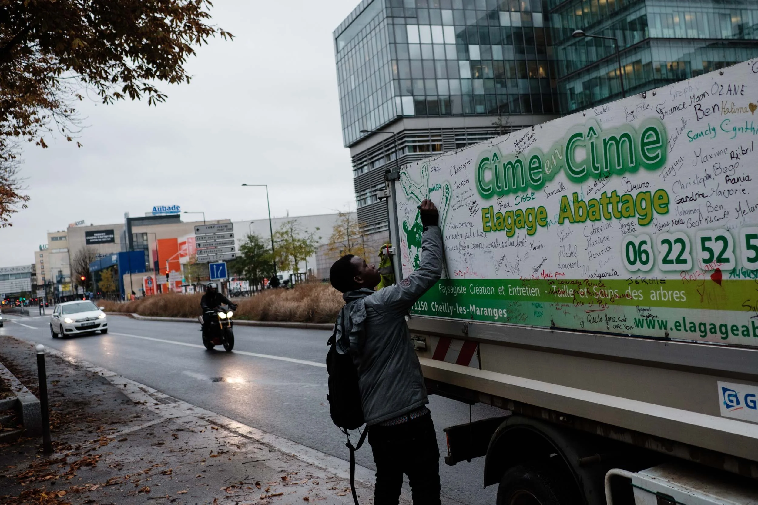  Un jeune homme inscrit son nom sur la camionnette de Patrick pour le soutenir. Tout au long de sa marche, Patrick a demandé aux personnes rencontrées d’inscrire leur prénom sur son camion. Ivry sur seine.  Novembre 2018 
