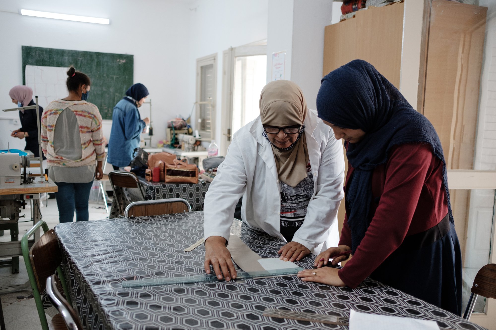  Dans l'atelier de couture du centre Cité commerciale de l'UNFT de Kairouan, Meriem prépare avec sa formatrice, la coupe d'une trousse qu'elle va réaliser. 