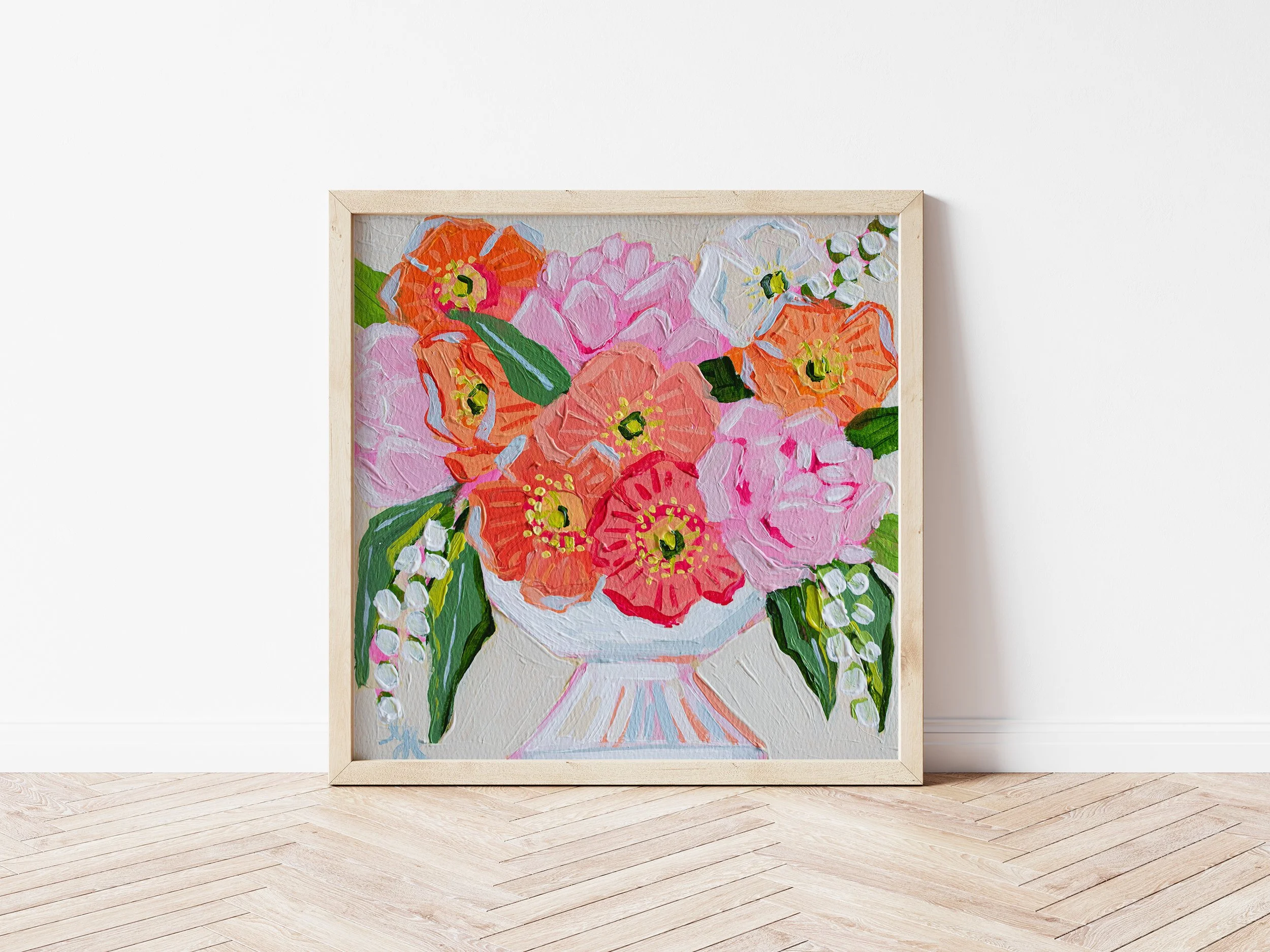 A colorful painting of a bouquet of flowers in a vase, leaning against a white wall on a wooden floor.