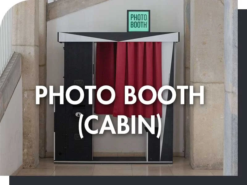 Fotokabine mit roten Vorhängen und einem grünen Leuchtschild "Photo Booth" oben auf dem Dach.