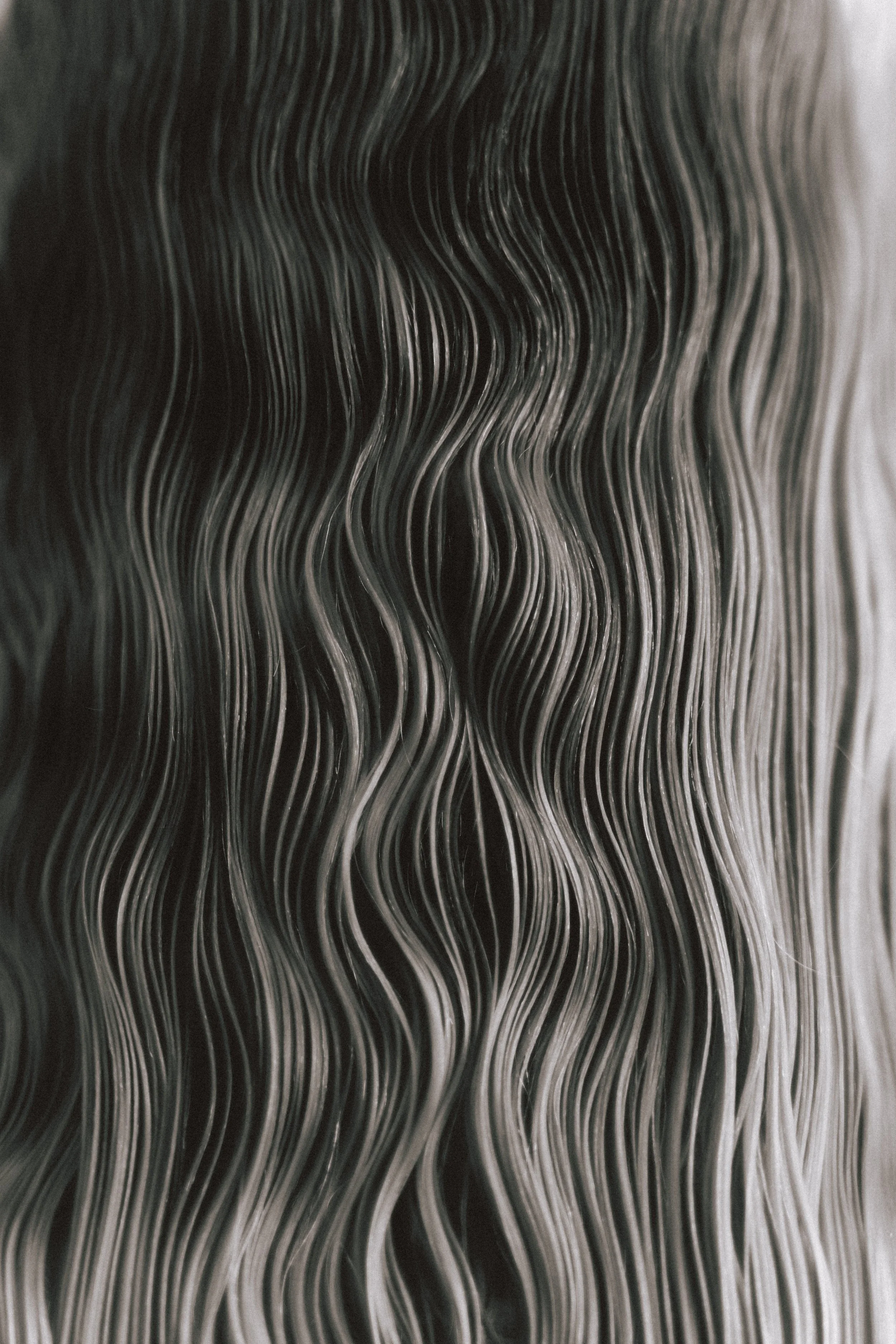 Close-up view of black and white strands, possibly hair, with wavy texture.