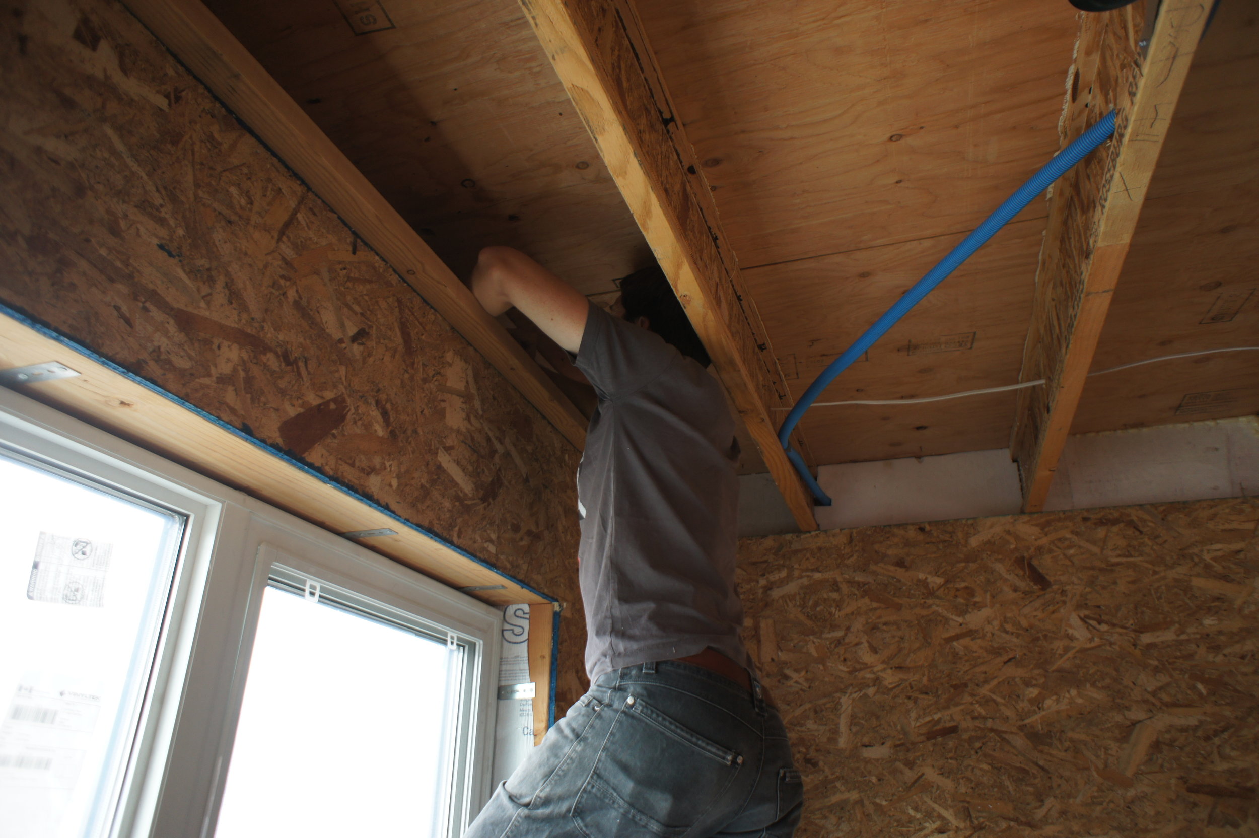 Eric air sealing the rim joist area with foam and caulk.