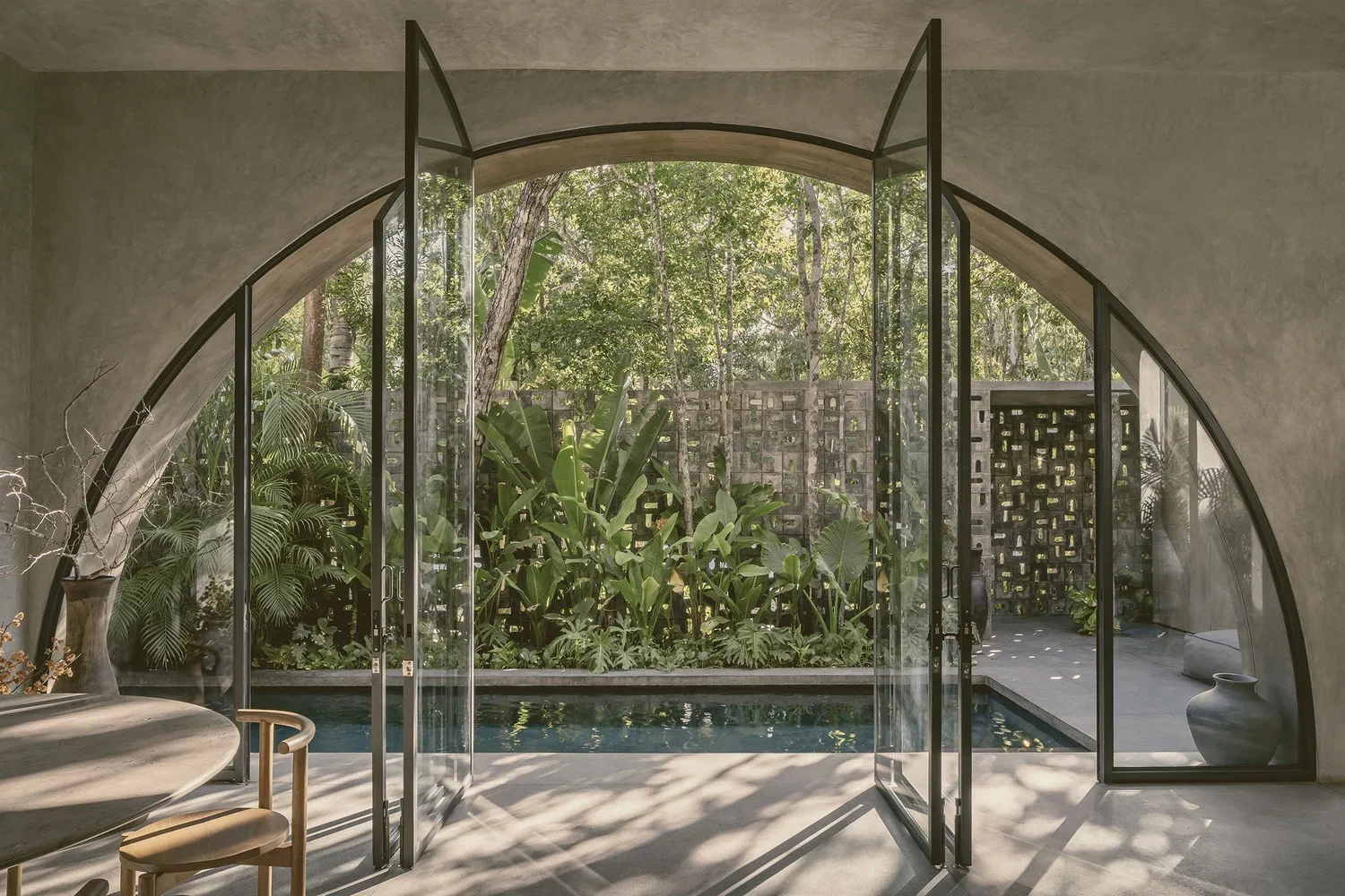 Villa Petricor Tulum — arched pivot window open to pool, tropical garden and celosia wall, CO-LAB