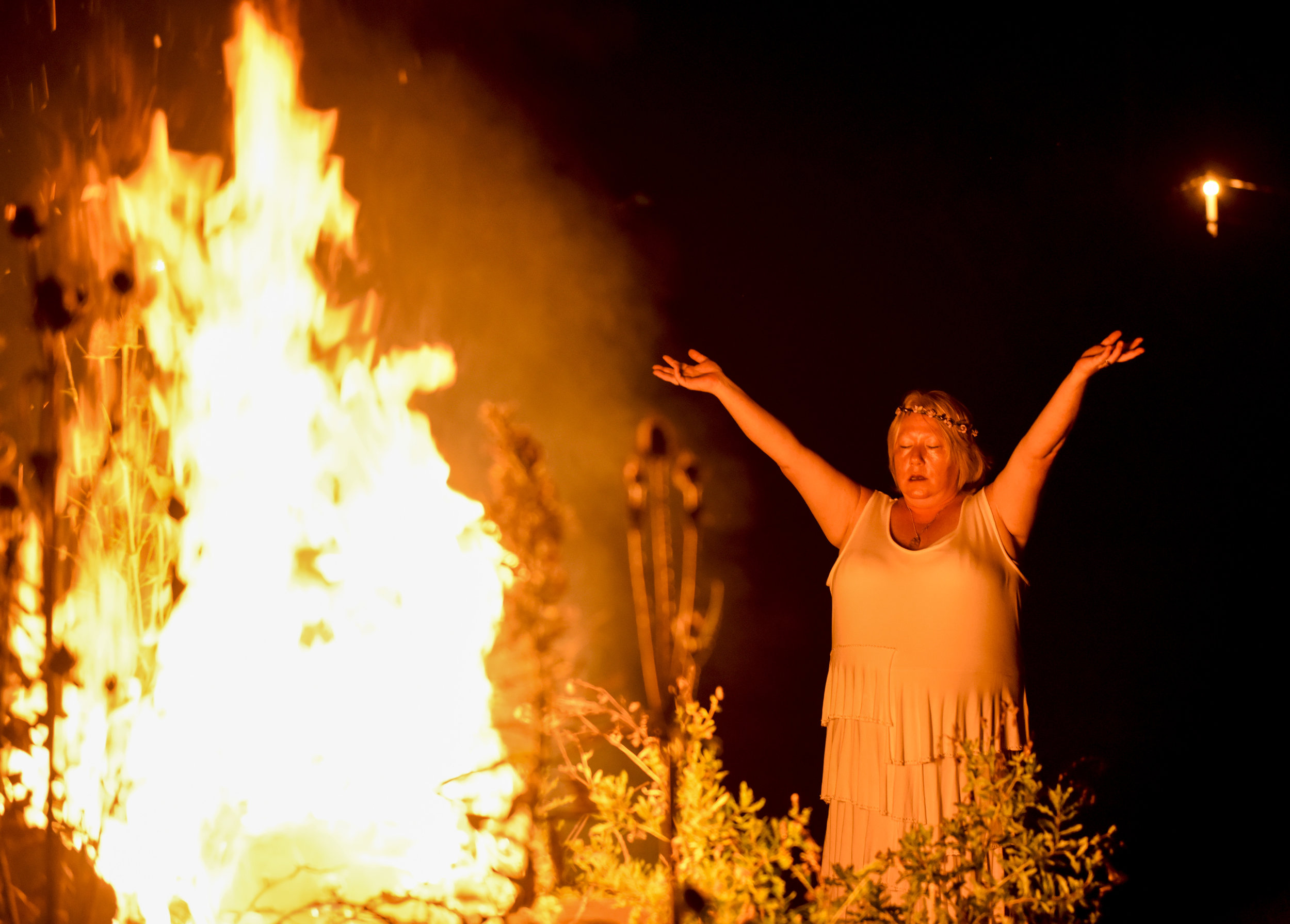  Local witch Red pays respect to the fire before the start of the Lammas and New Moon celebration Saturday, Aug. 11, 2018. The celebration commemorates the coming harvest, and the new moon represents the start of something new. 