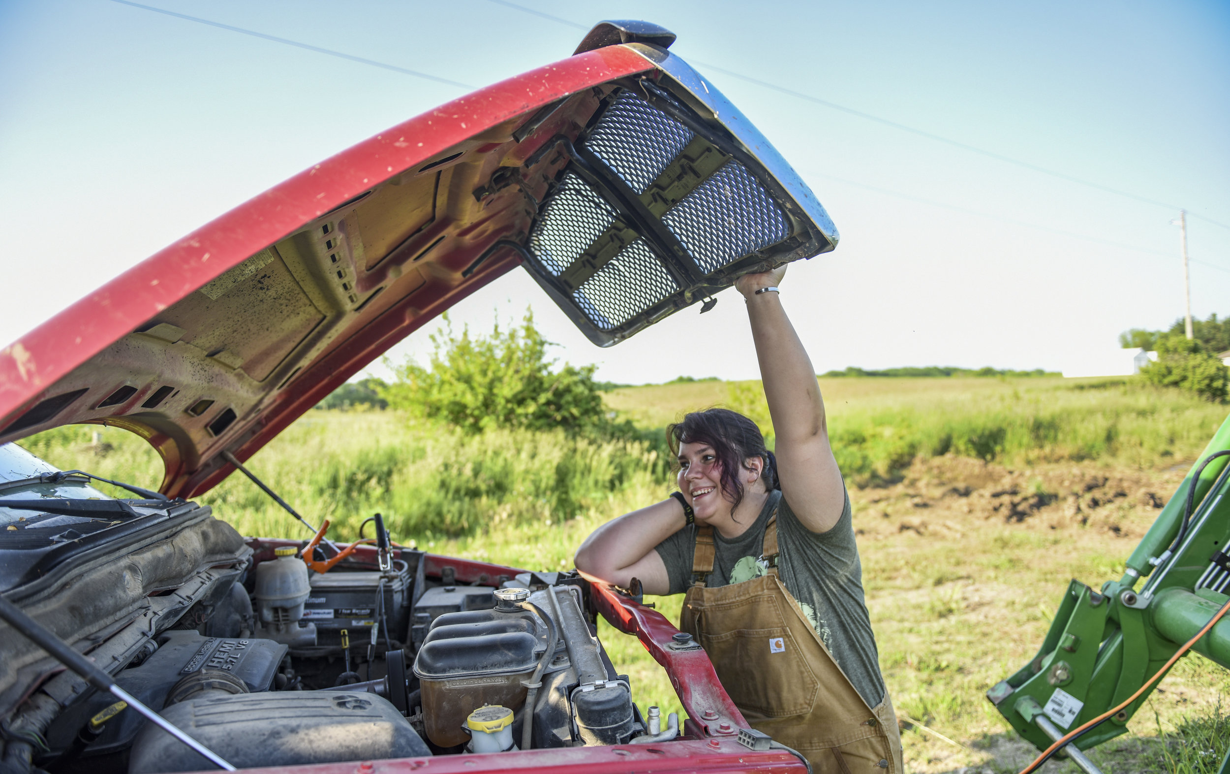  Julia DePauw holds the hood of a truck up while trying to jump-start a tractor that lost power Sunday, June 9, 2019, in Port Byron. 