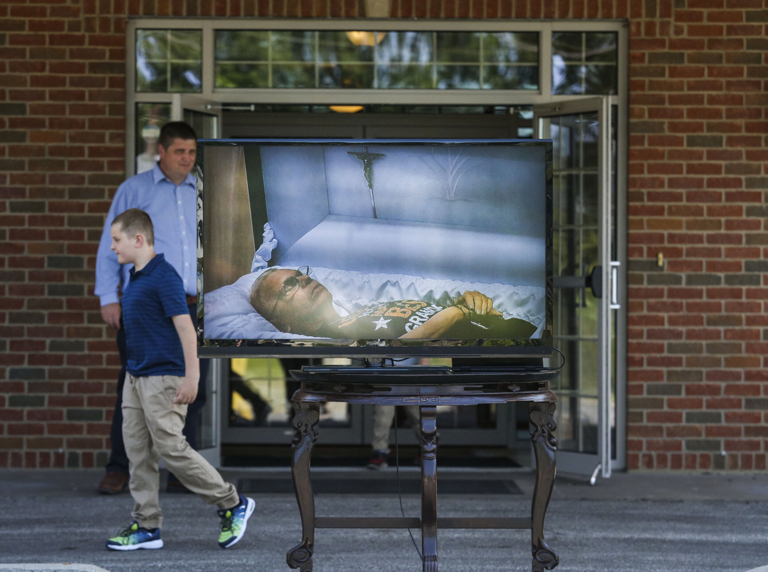  Jason Gustafson and his son Adrew Gustafson, 8, of Cambridge walk behind a television that live streams their family member Joseph Bernard Burns' casket during a drive-thru only visitation. Sunday, June 14, 2020 at Wheelan-Pressly Funeral Home and C
