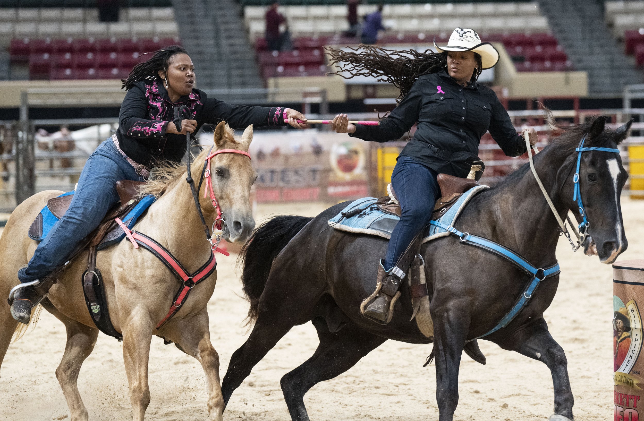  Brittaney "Britt Brat" Logan passes a baton to Kisha "KB" Bowles while competing in the relay racing during the Bill Pickett Invitational Rodeo, at the Show Place Arena. 