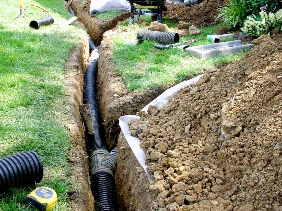 Underground drainage pipe being installed to manage water in a residential yard