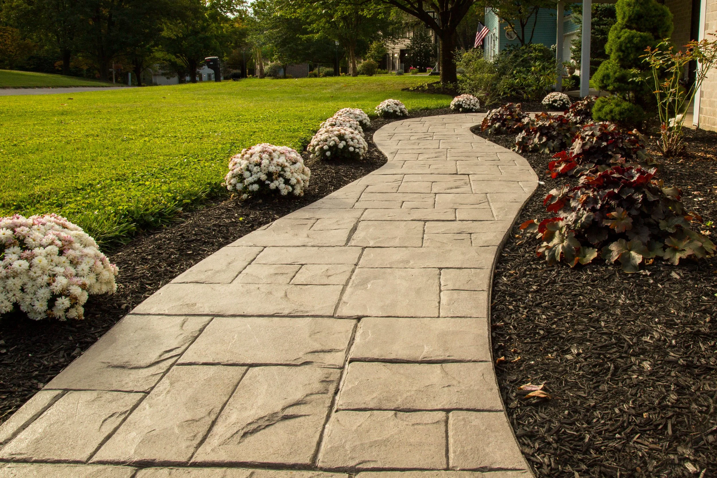 Curved decorative stamped concrete walkway through a residential landscape
