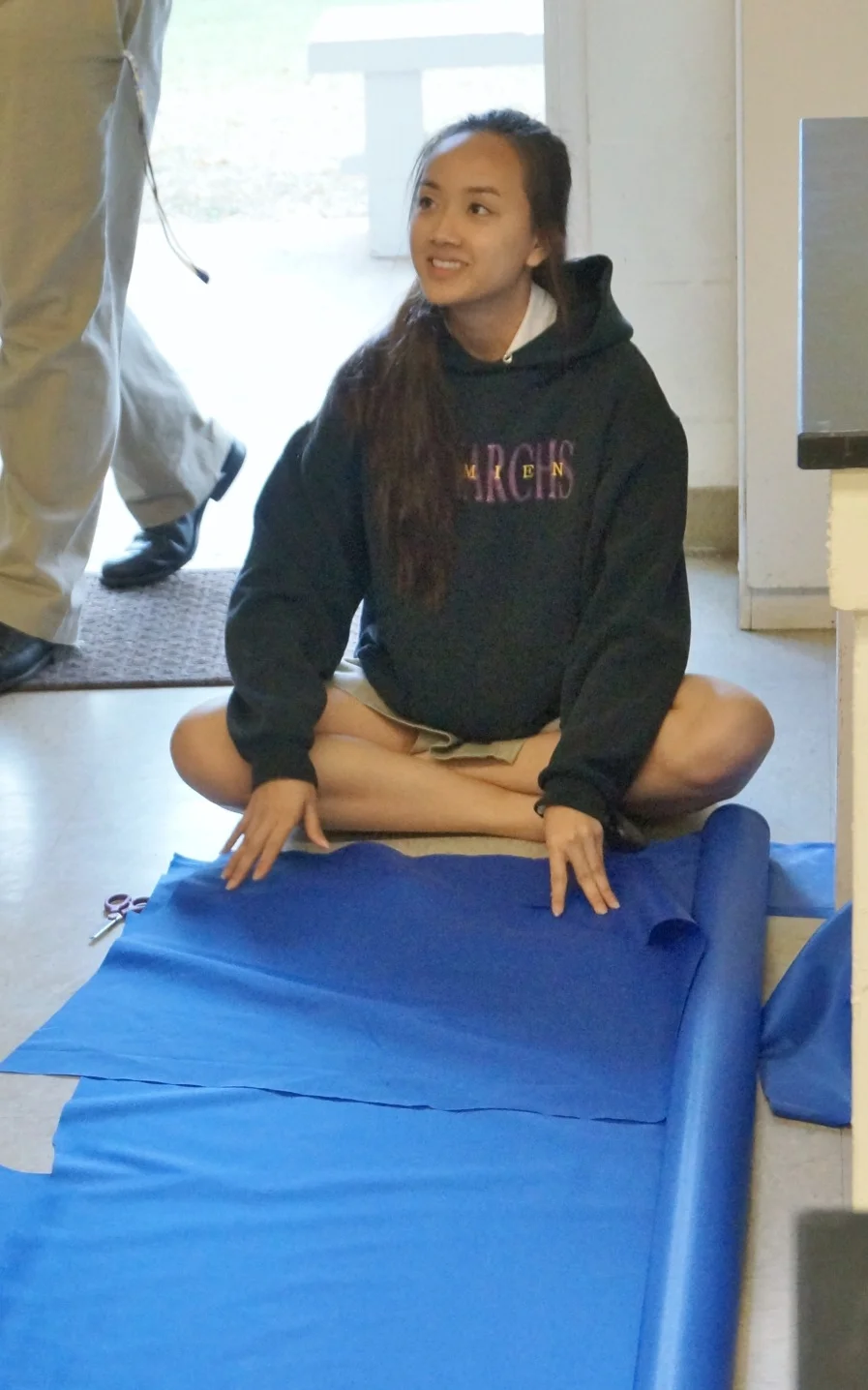 DMS Senior, Theresa Tran takes a break from cutting the lining for the bumpers as she speaks to fellow Safety team member.