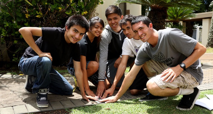 Seniors and friends, (l-r) David Ybarra, Lin Shibata, Logan Santiago, Ethan Kaimalu Diaz, and Jared Miller place hands on the “2016” paver just laid in the Viriliter Age Pathway on the Damien Memorial School campus.