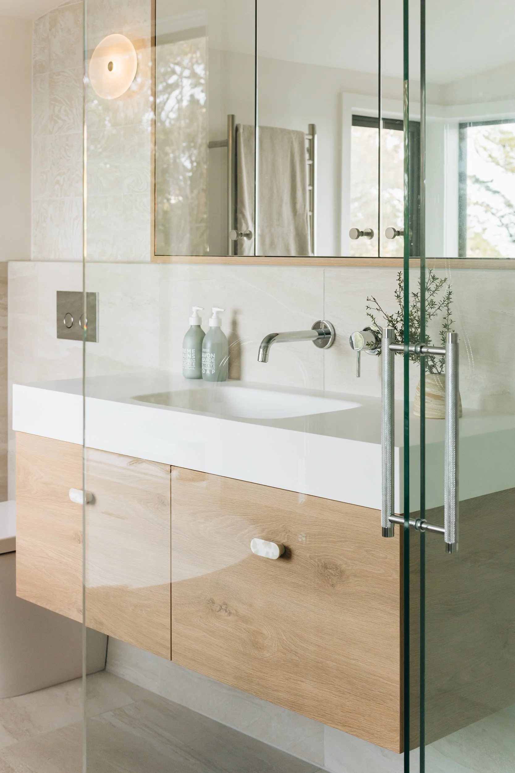 Light-filled bathroom with custom vanity and large mirror reflecting Wellington Harbour