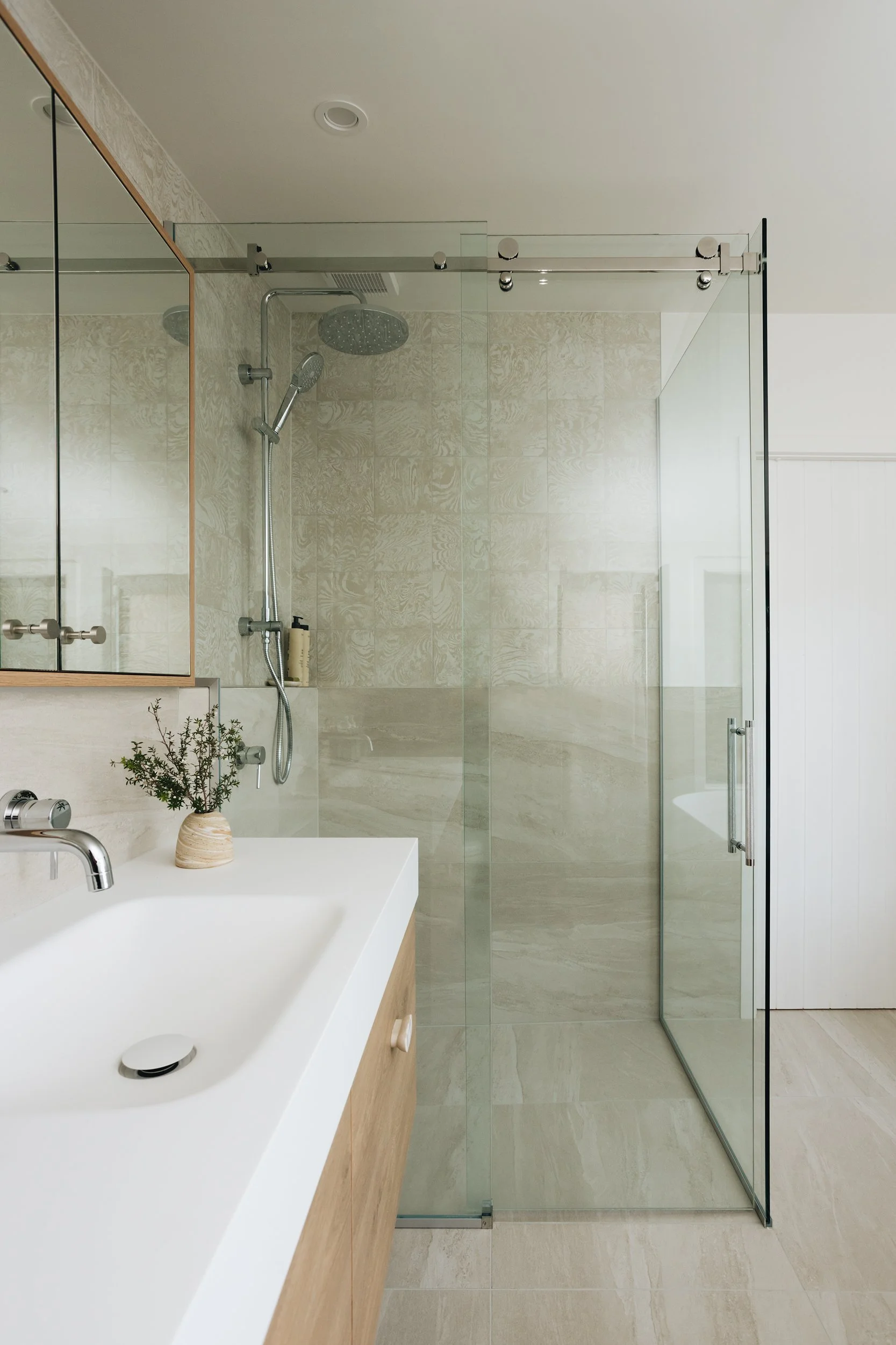 Tiled, modern bathroom interior design with frameless shower and custom vanity