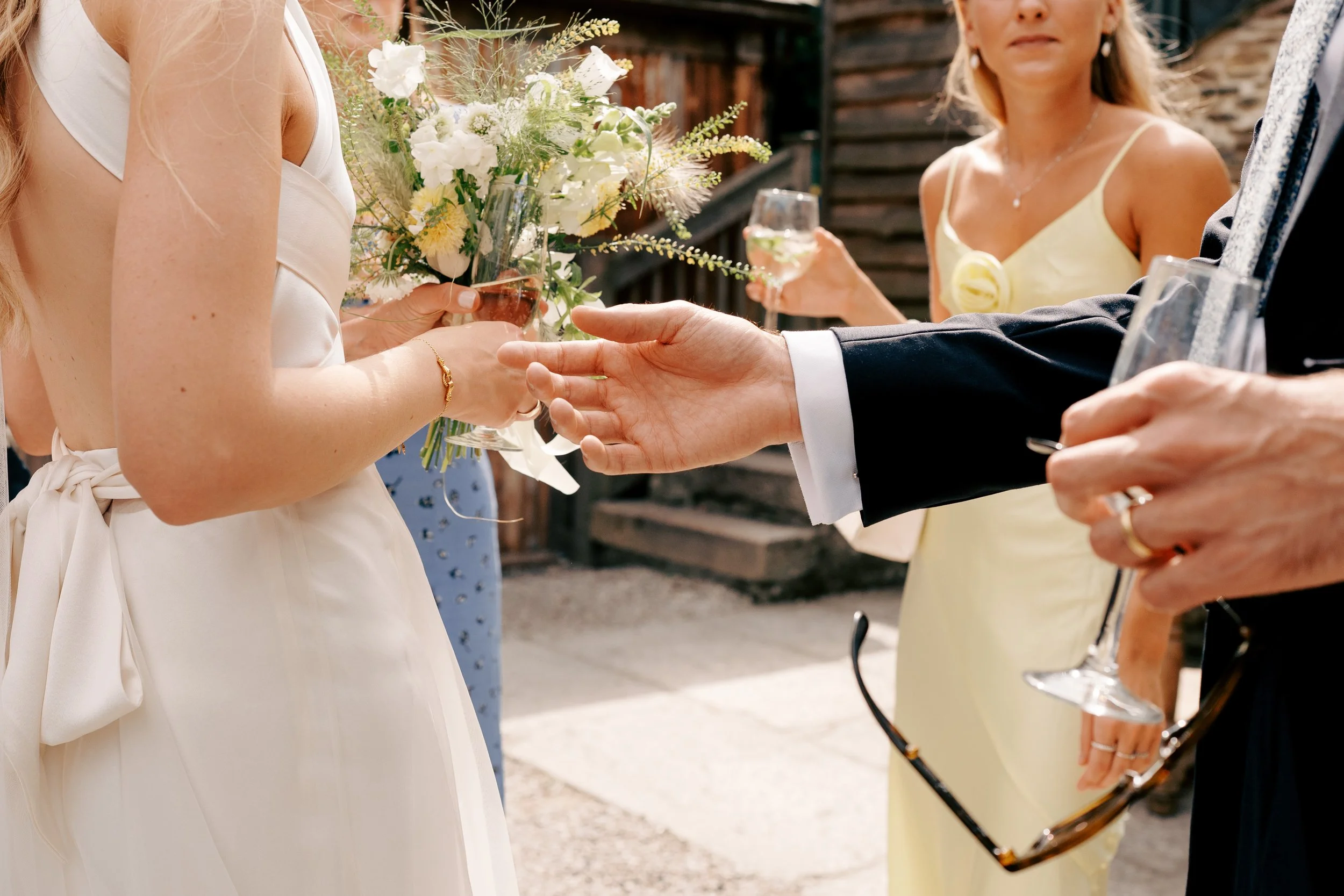 Black and white photo of people sitting at a table, with a woman in focus, leaning her head on her hand, and a man in a suit in the background, all appearing to be engaged in conversation.