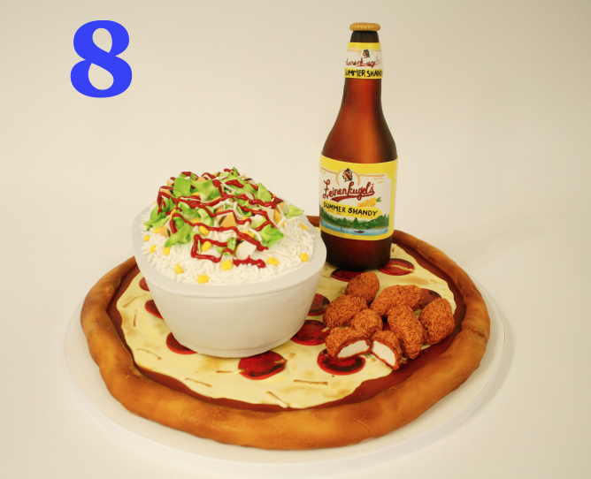 Cakes that look like other foods are some of the most fun to make! We think it’s the playfulness of one food item (cake) disguised as another. It’s especially fun when we make something sweet look like something savory. This junk food cake has all the classics (pizza, wings, beer, and a Chipotle burrito bowl. And yes, this decorator did go out and get Chipotle after finishing the cake!