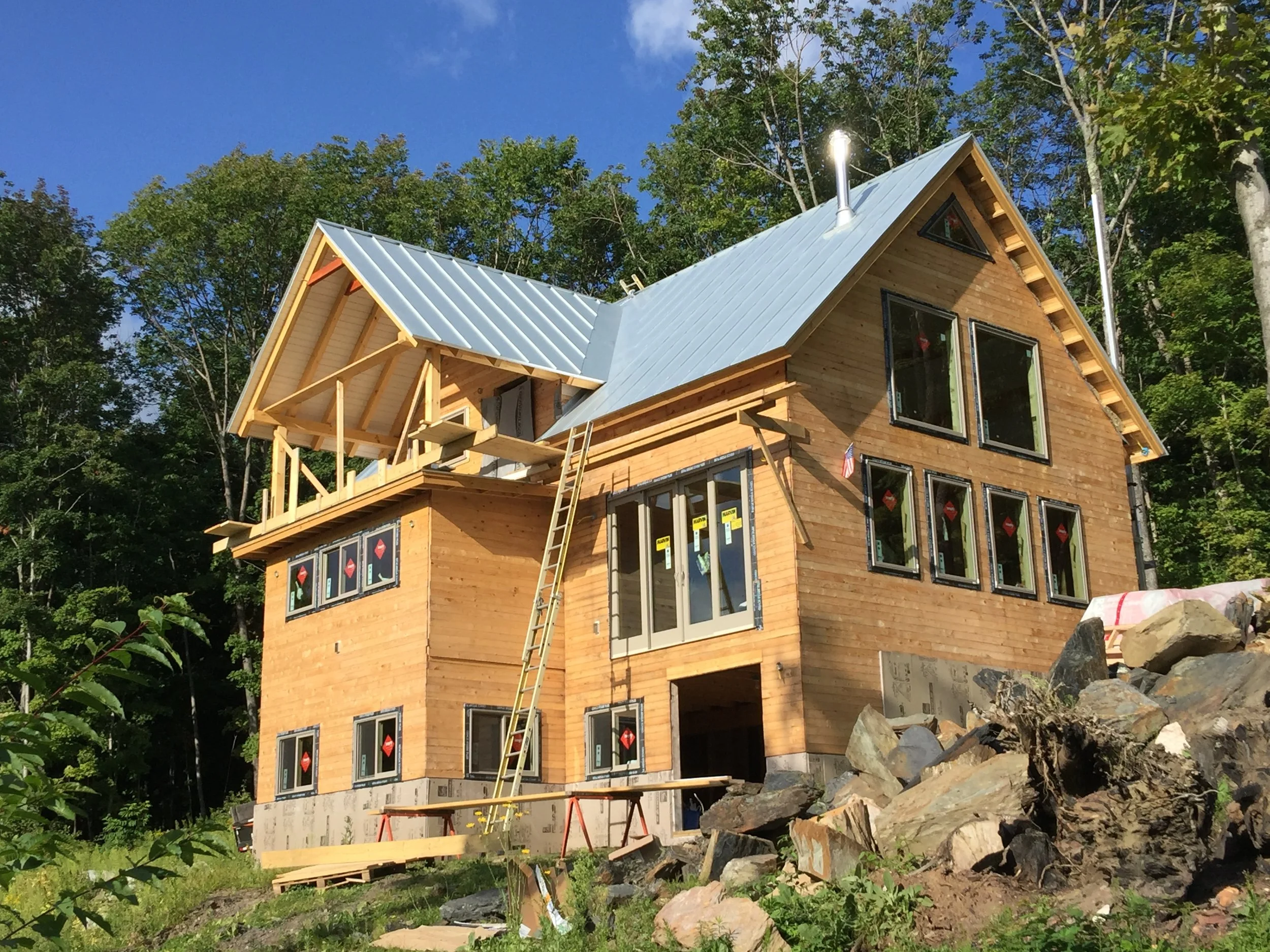 A house under construction with wooden siding and a metal roof. Construction by Corrigan & Klein Artisan Builders.