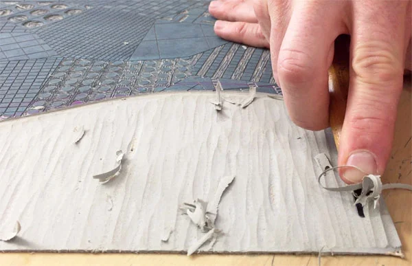 Carving away the linoleum block’s negative space with a “U” gouge.