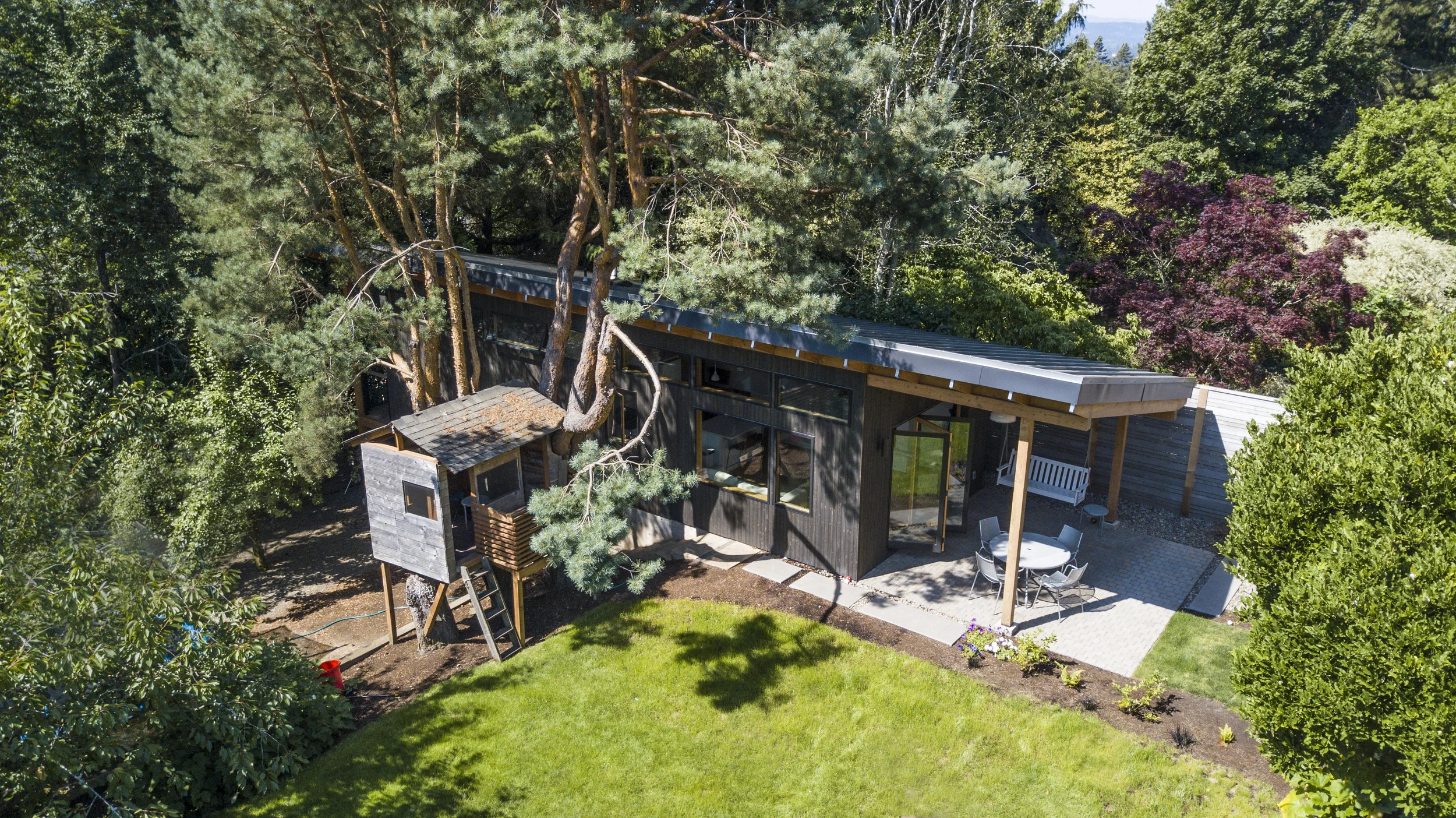 Location: Portland, OR Design: Green Gables Construction: Green Gables Photography: Stefan Lerch This modern ADU, located in the backyard of a SW hills home, is small, but conspicuous. Comprising a cozy 560 square feet, the efficient layout situates the private bedroom and bath to the rear of the home, allowing for a bright and open living area. Continuous clerestory windows bring in a generous amount of daylight, and the large accordion door allows the interior space to expand out onto the covered entry patio. Built-in cabinetry along the west wall adds to the functionality of the space, providing storage, seating and a workspace. Doug fir roof rafters are exposed on both the interior and exterior, emphasizing a clean structural layout while adding warmth and character throughout.