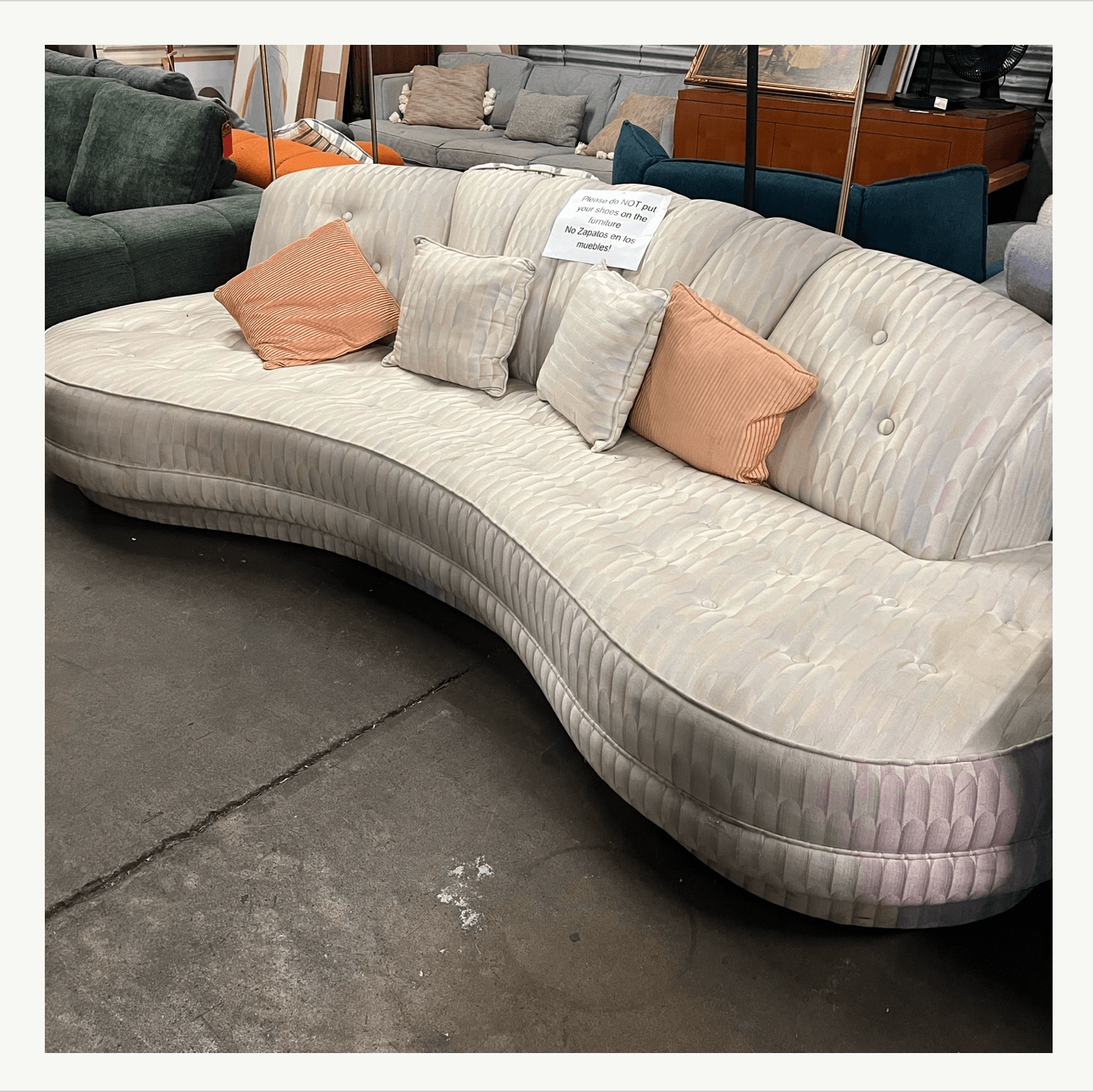Curved vintage Vladimir Kagan sofa in worn cream quilted fabric at Poor Honey's Oakland — a prime candidate for reupholstery by Revitaliste