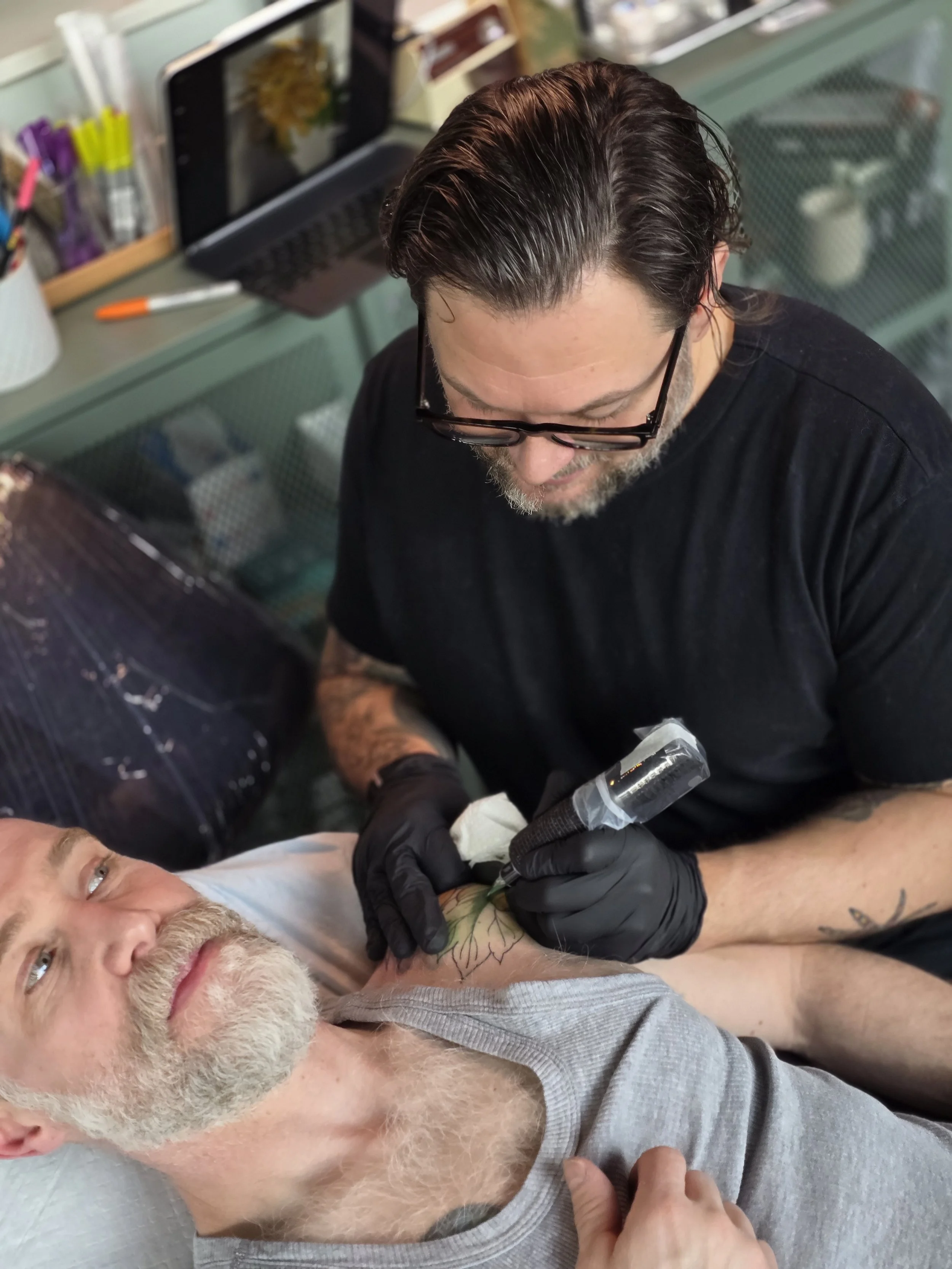A tattoo artist works with focus and care during a tattoo appointment, showing the collaborative and personal side of the tattoo process.