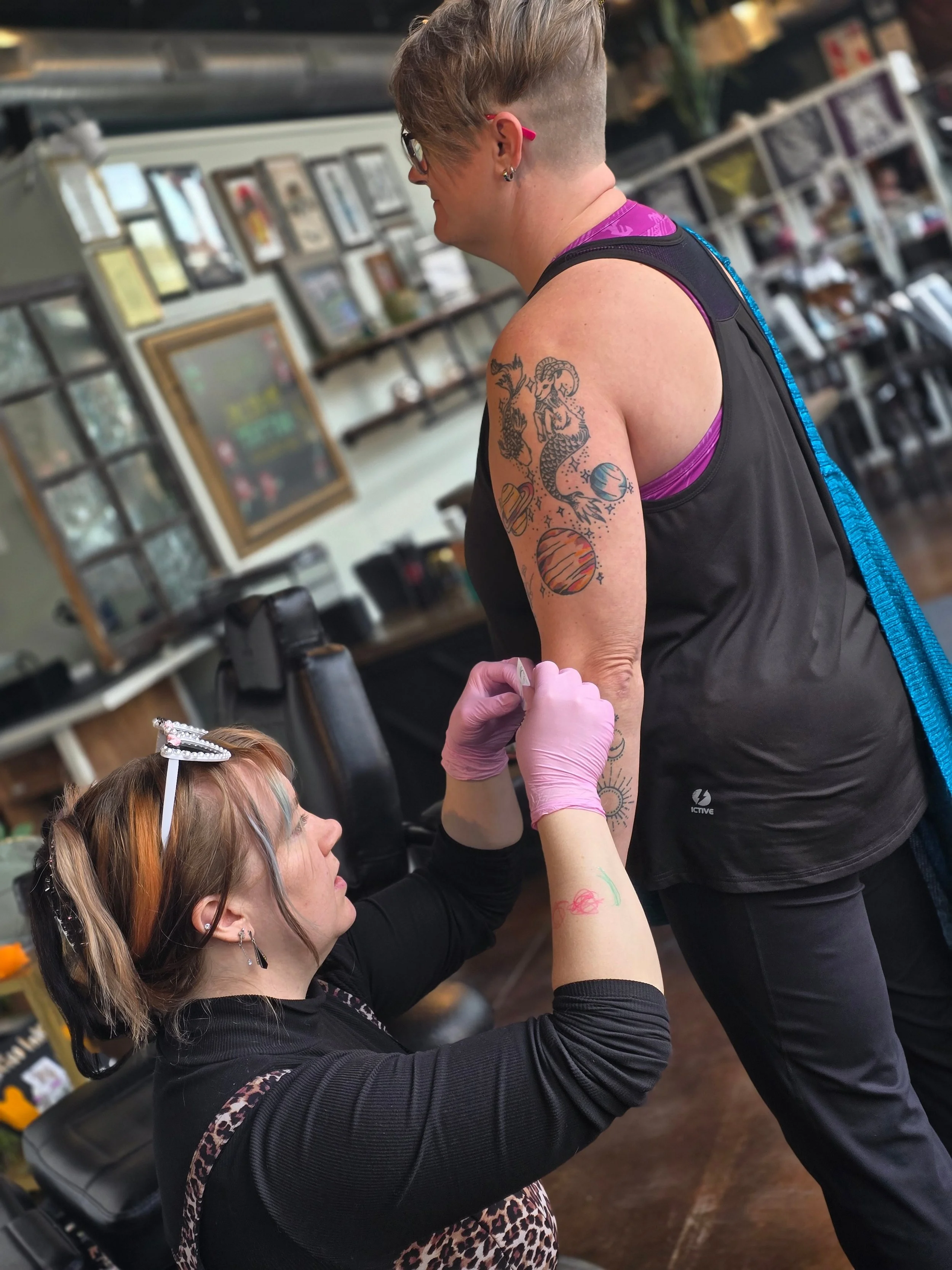 A tattoo artist and client collaborate on placement and design, highlighting trust, communication, and body autonomy in the tattoo process.