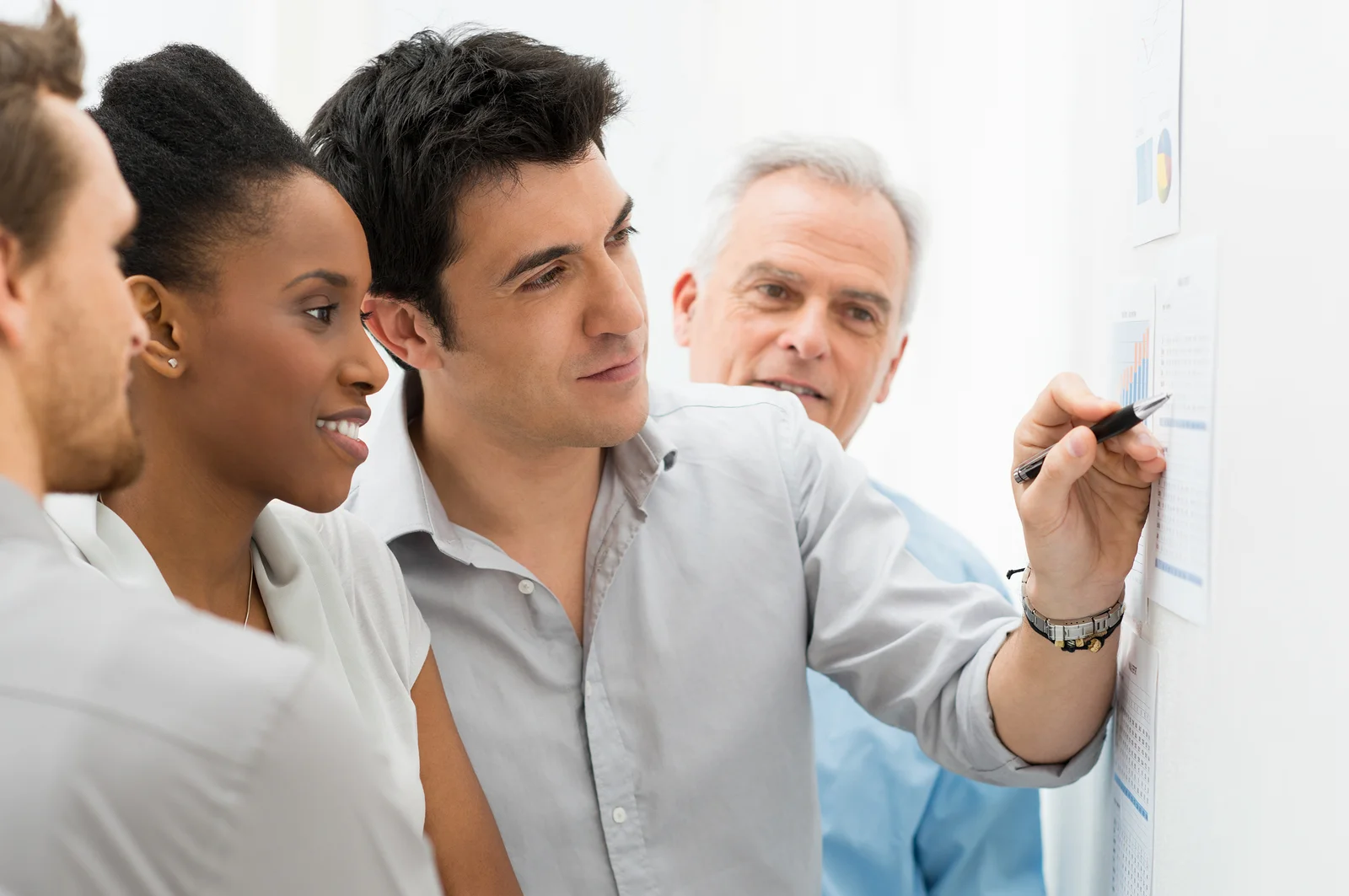 Group Of Business People Analyzing Graphs and Charts in Office