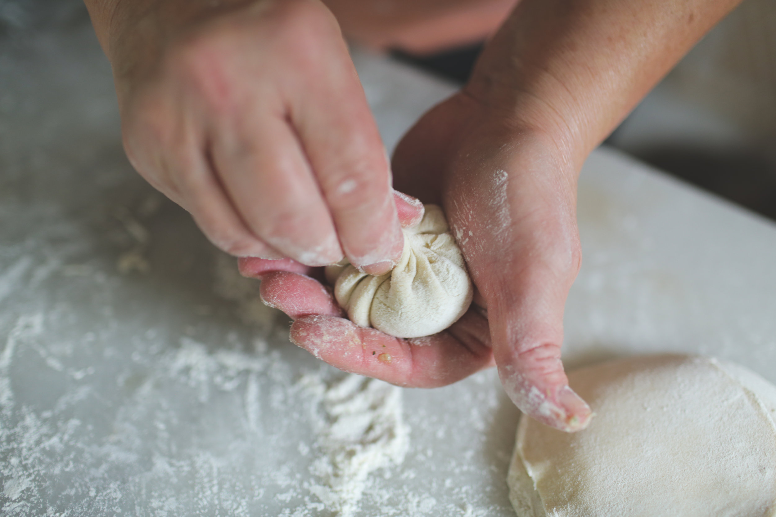  18. Firmly pinch the neck with your fingers and twist it as you turn the dumpling with the other hand. 