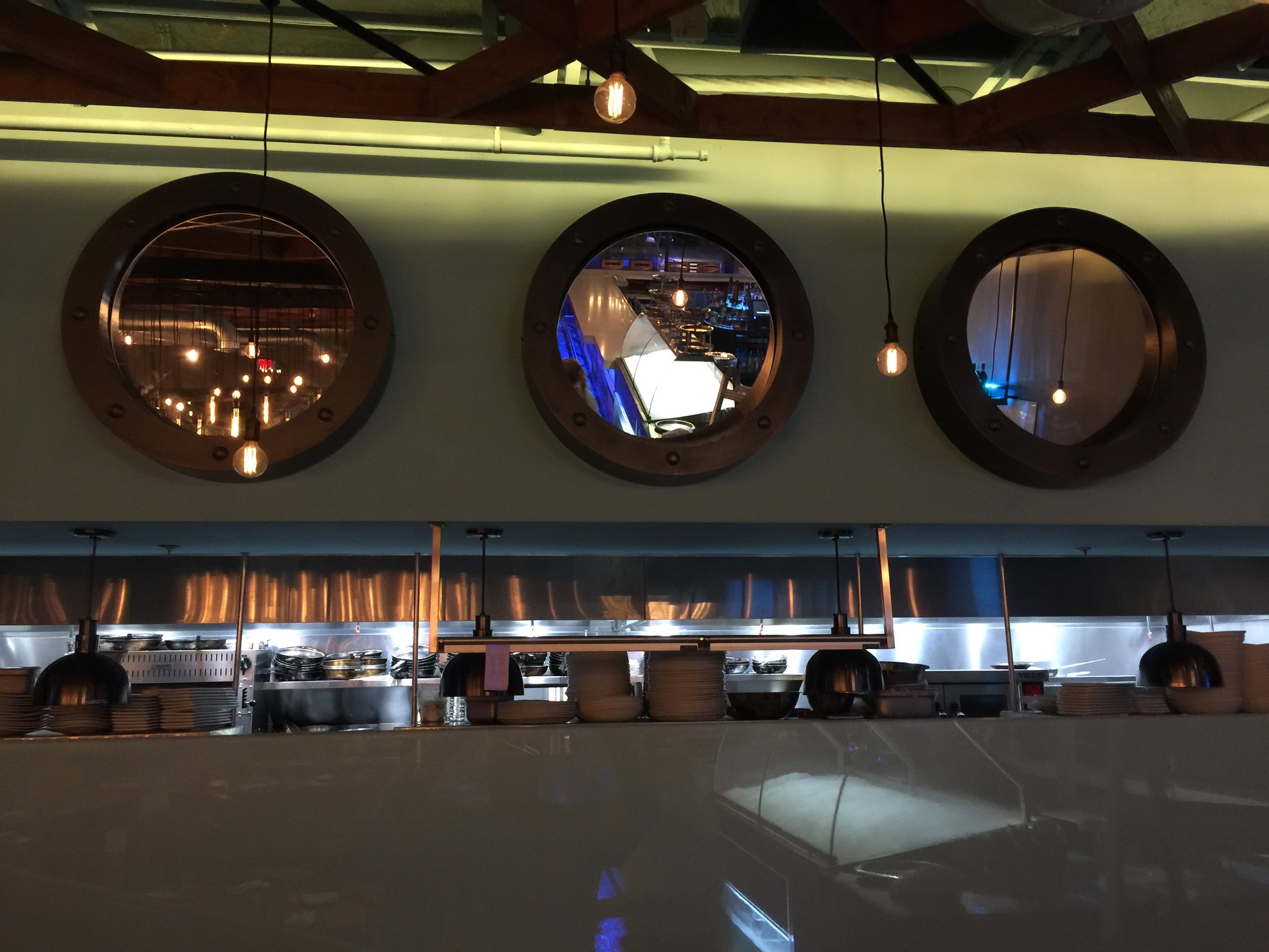 Pivoted Porthole Mirrors angle 45 degrees downward so viewers see themselves and the dining room, not the ceiling