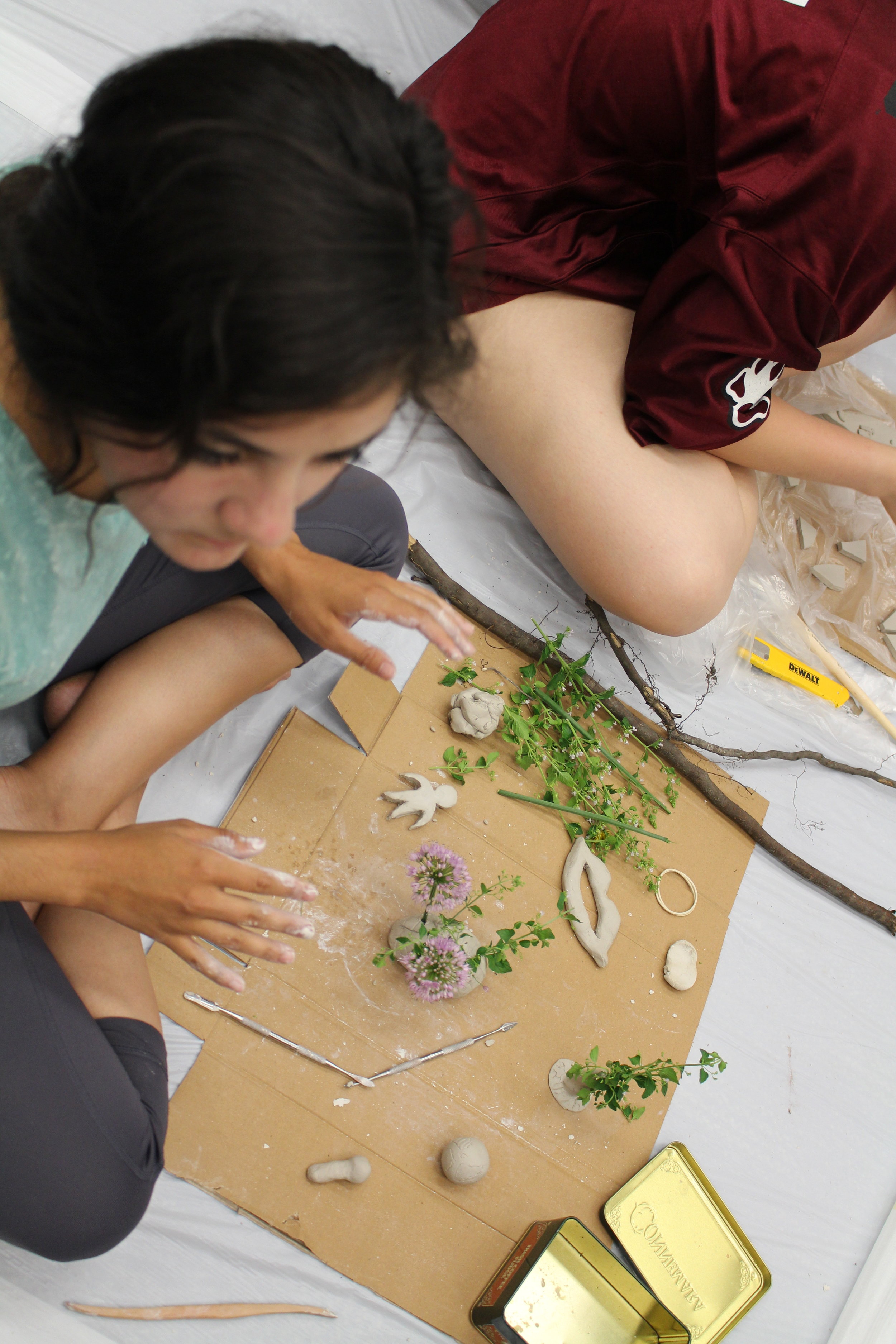 Picture of person working on their clay sculpture also using plant material