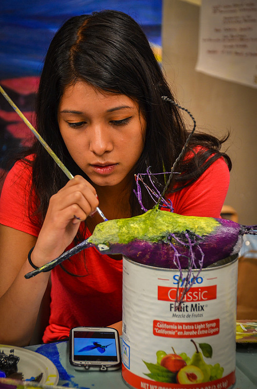 Person painting a yellow and purple bird