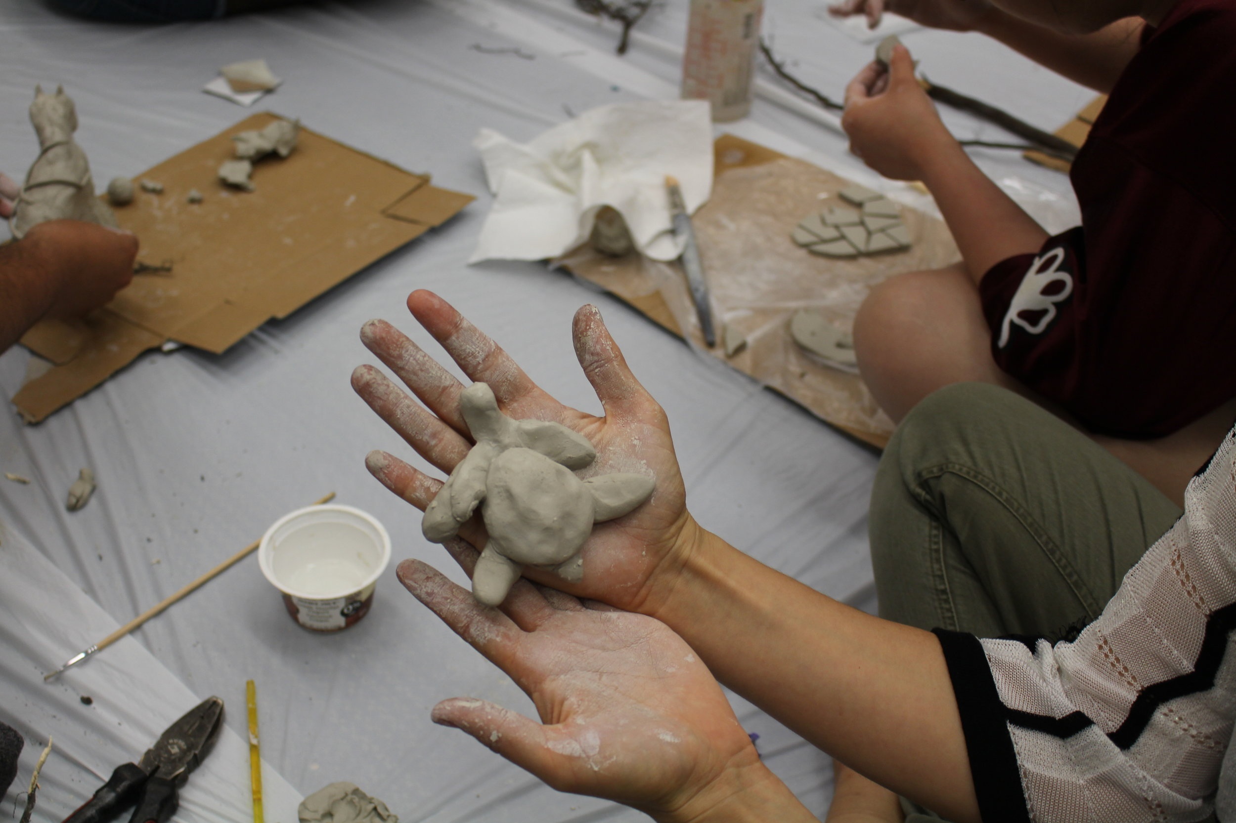 Picture of a turtle like clay sculpture on someone's hand.