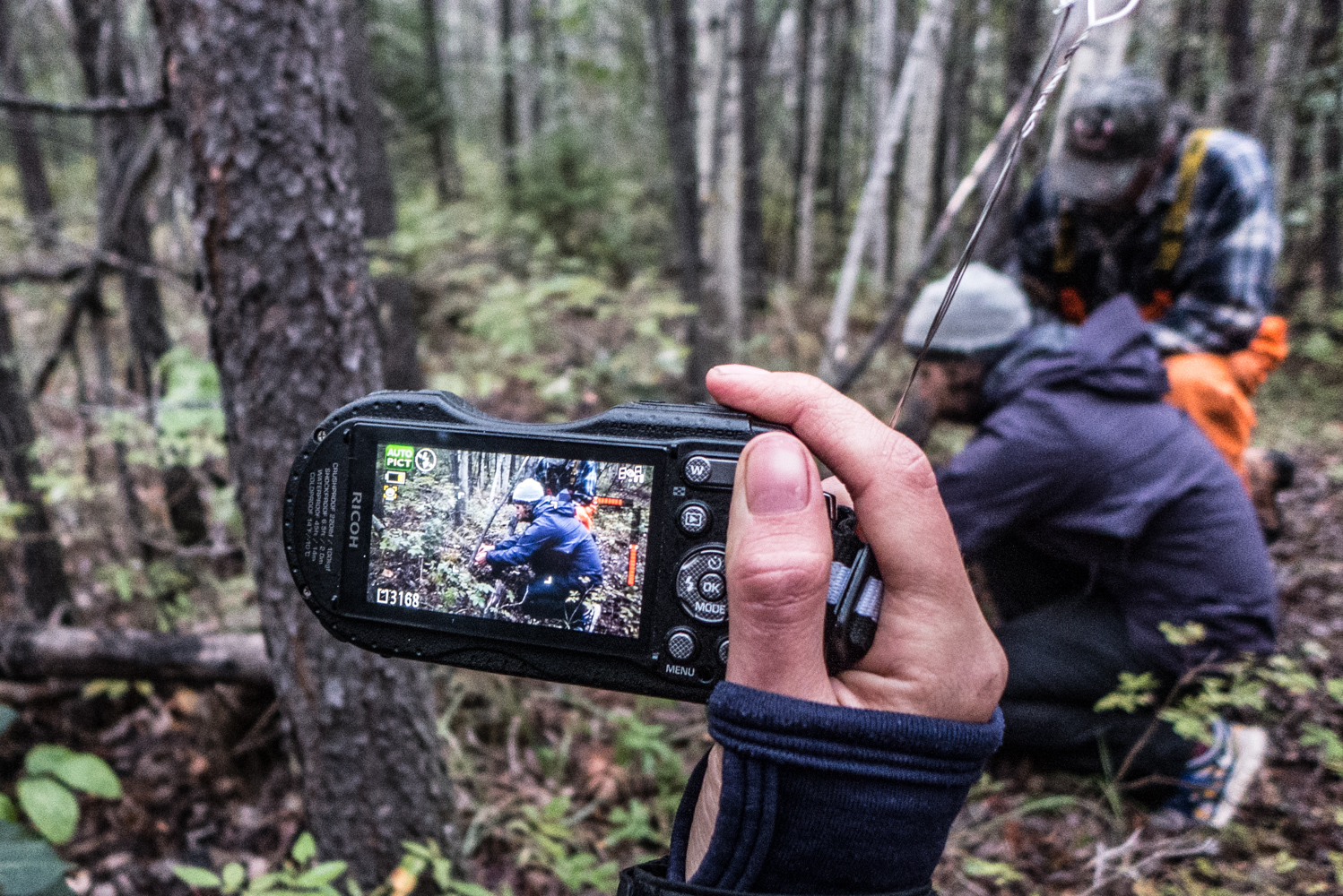  Tara Joly photographing Roy Ladouceur showing Jessica Weber how to set a rabbit snare, August 2015. 