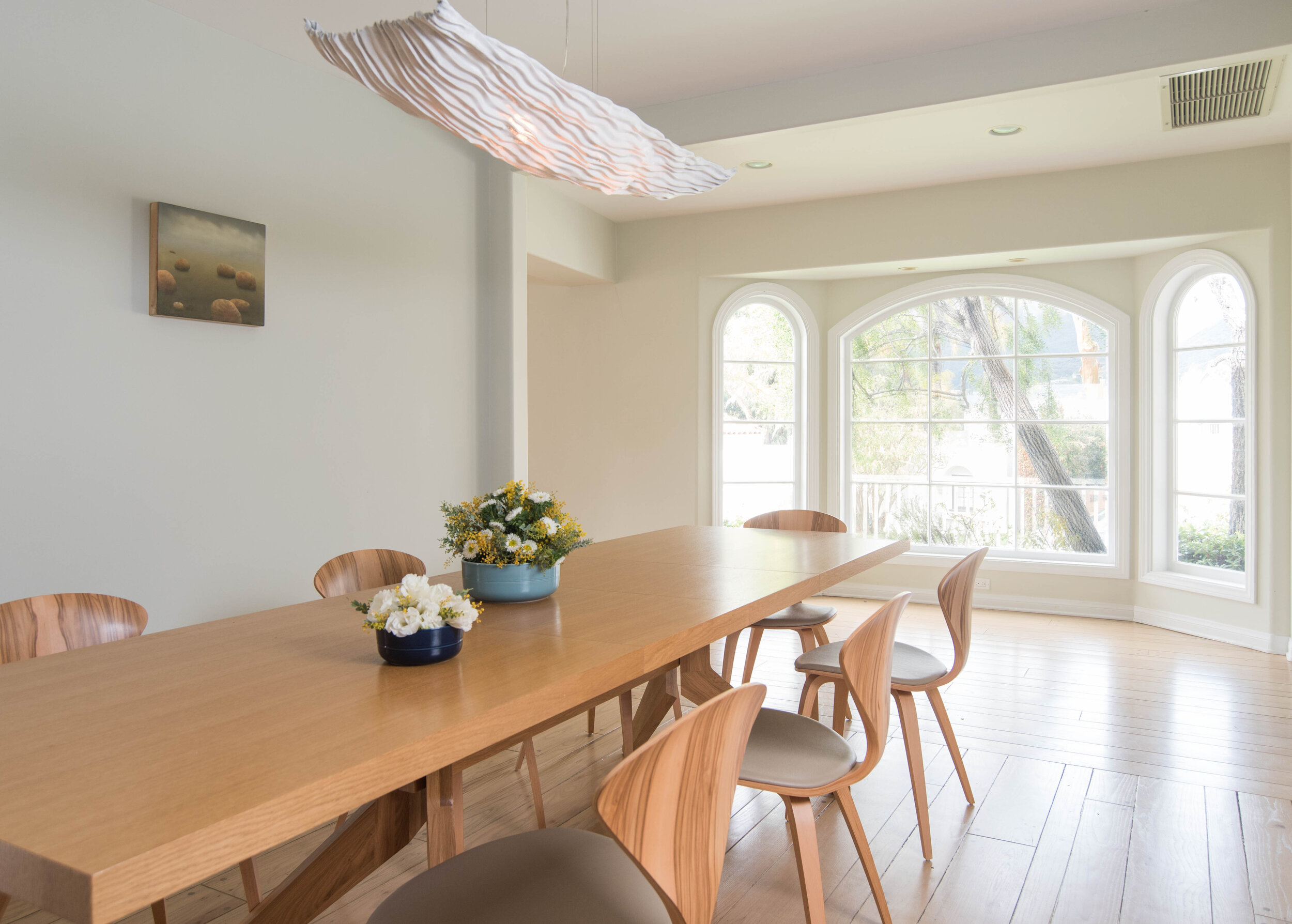    A serene dining room designed to feel soft and light.  A lightweight chandelier is reminiscent of ocean waves.   