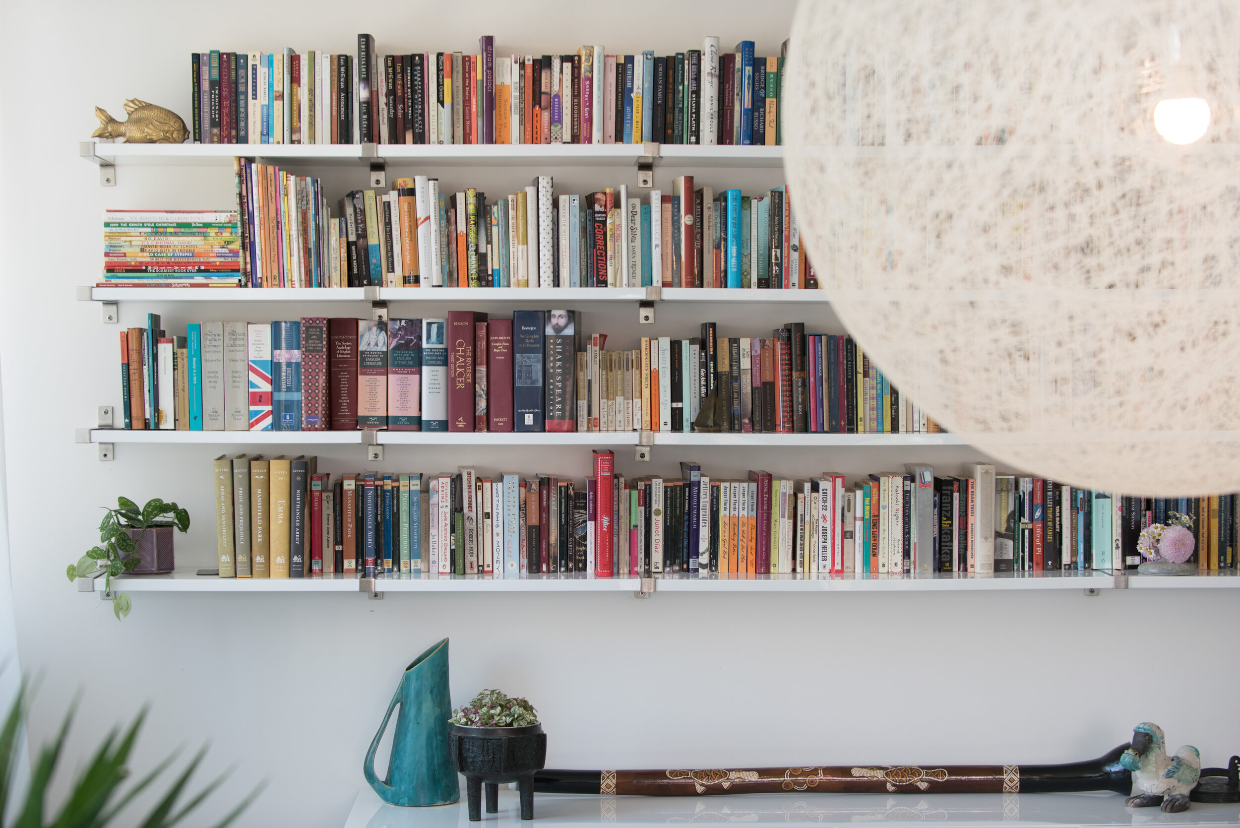 White floating bookshelves and large woven pendant light in foreground