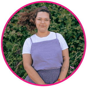 Celie Nigoumi in a fuller body shot, her hair windswept, subtly smiling at the camera