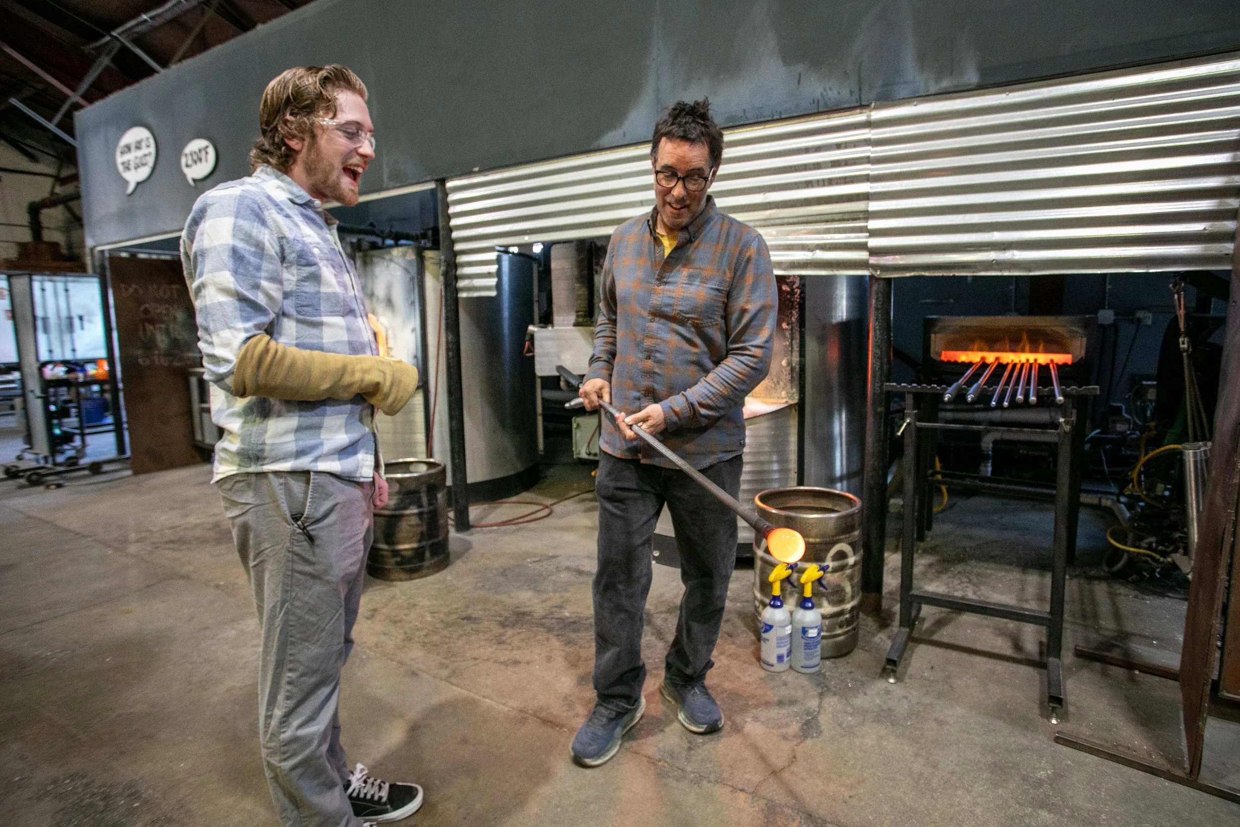 Two men craft high end hand blown glass tableware.