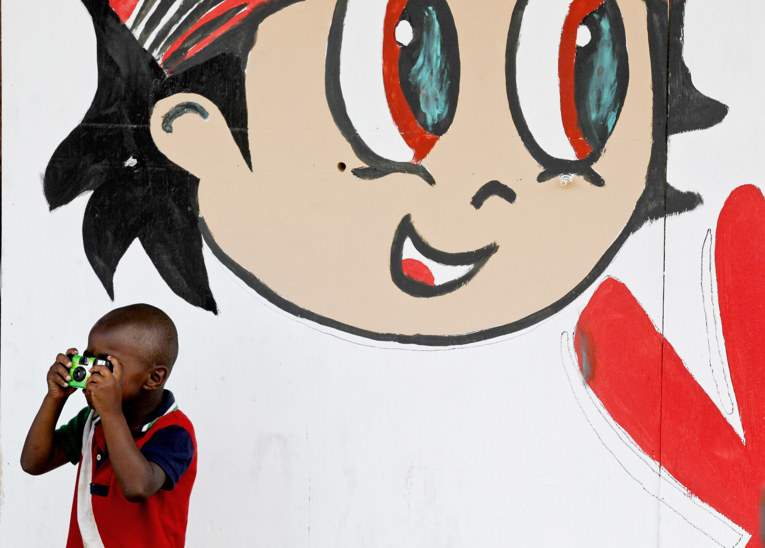 A young bystander photographs police officials working outside the scene of a workplace shooting that resulted in four deaths on Cherokee St. in St. Louis, Mo. on June 13, 2013.