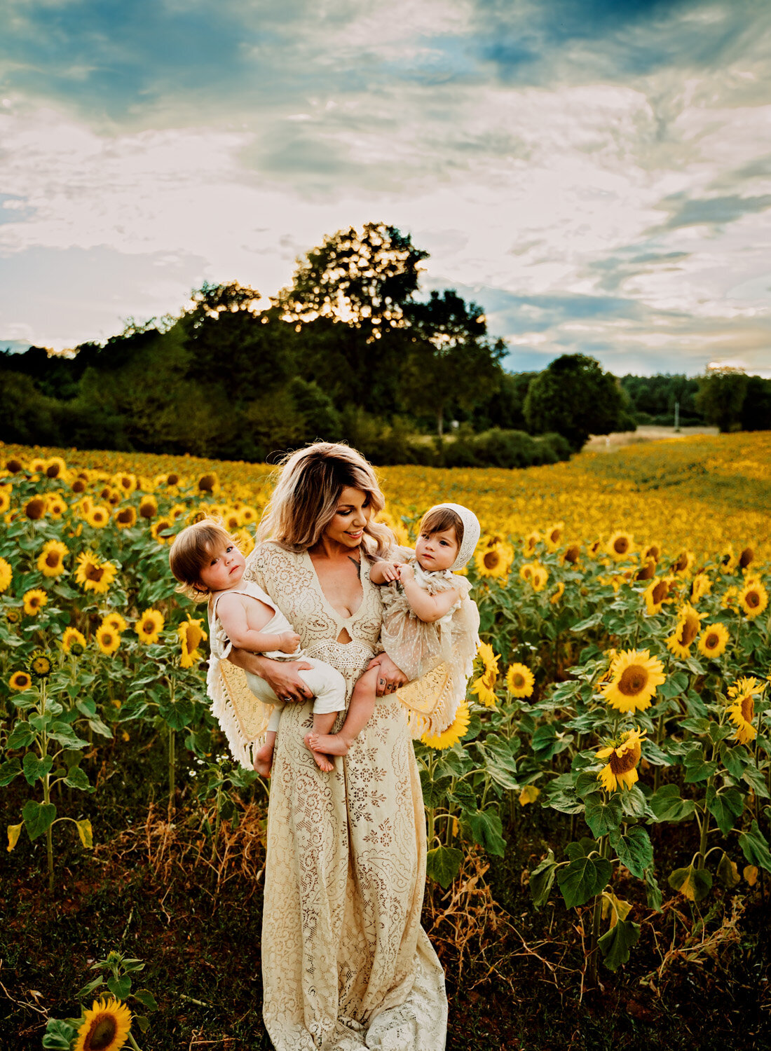  Beautiful family photo session in s big sunflower field. Young family with twins in boho outfits and flutter dress by ramstein kmc family photographer sarah havens - photo of mother holding twins 