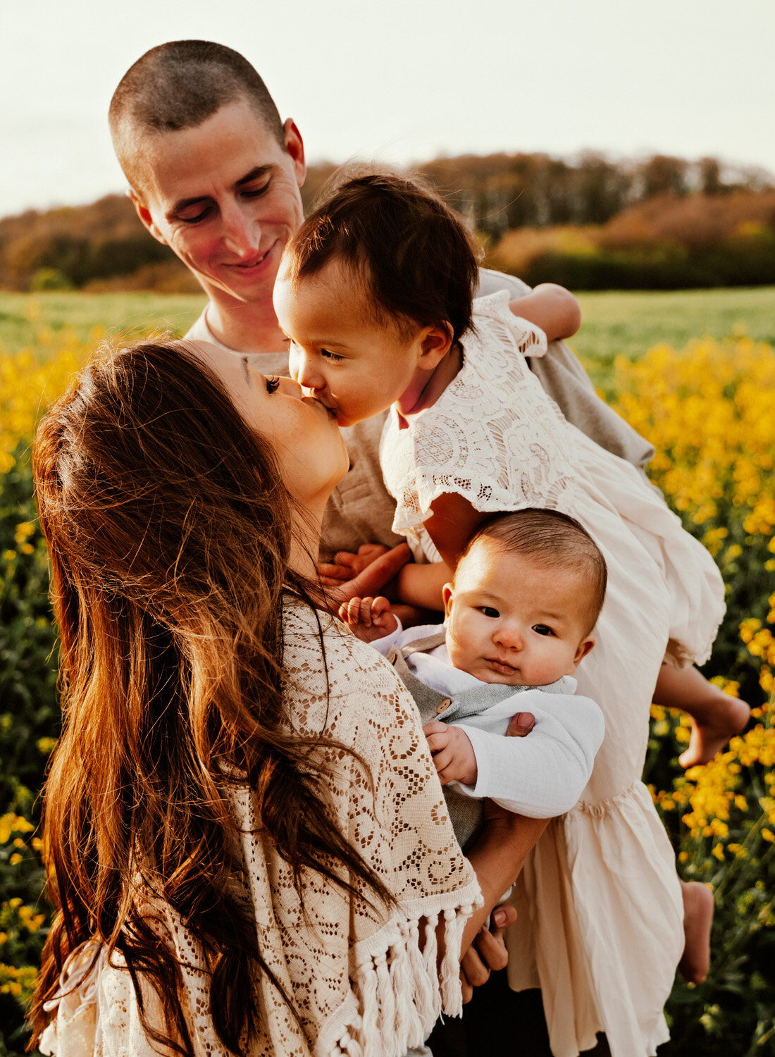  Beautiful Family with 2 small children in bohemian outfits playing in yellow rapeseed fields in Rheinland-Pfalz in the German country side. Lifestyle Family Photo Session by Sarah Havens, serving the Ramstein KMC and Kaiserslautern area. 