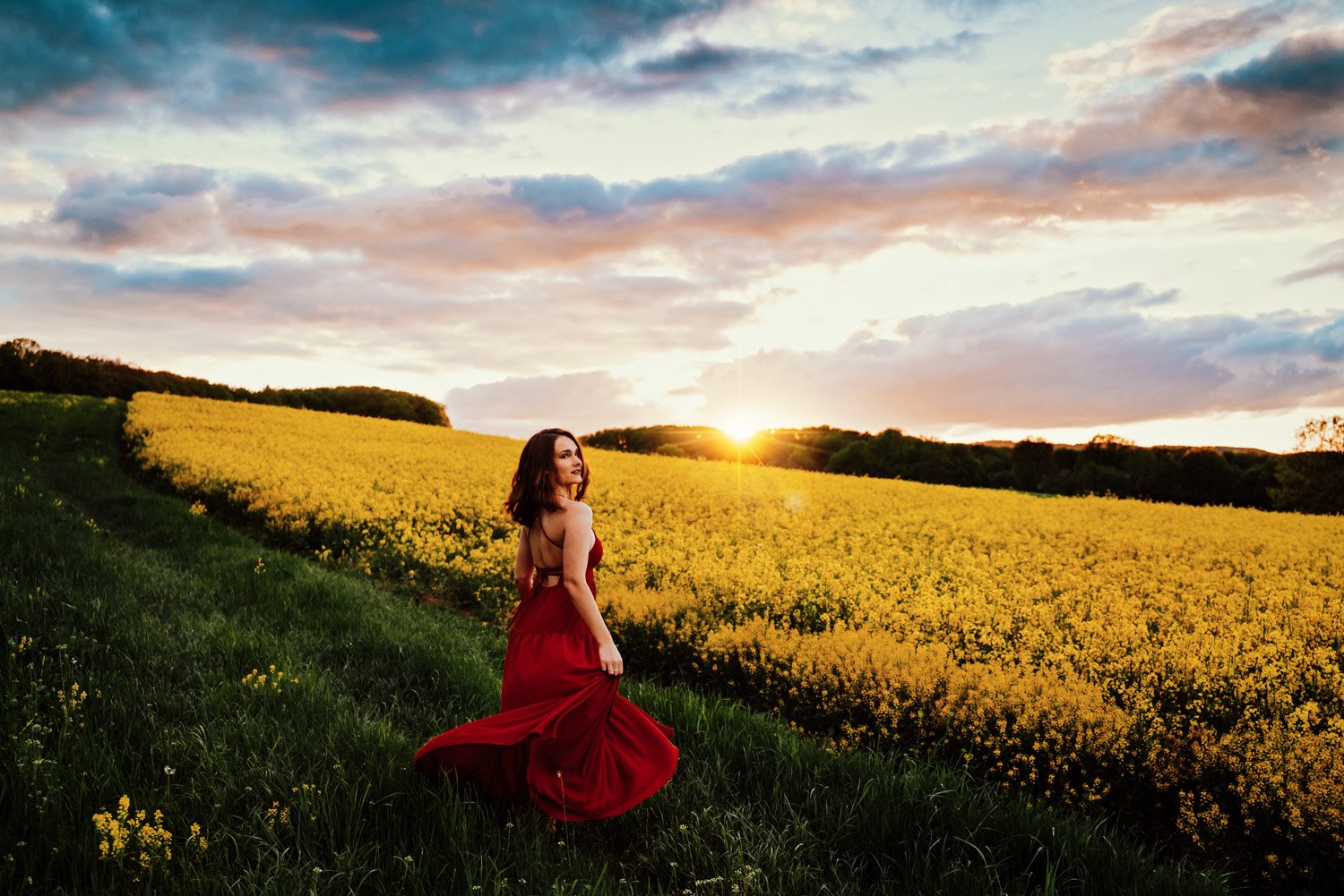 portrait-of-ramstein-high-school-senior-girl-in-red-dress-dancing-in-front-of-yellow-rapeseed-flower-field-by-kmc-family-photographer-sarah-havens-kaiserslautern.jpg