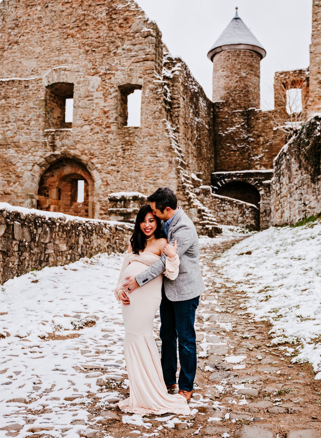 expecting-parents-in-intimate-pose-and-formal-outfits-at-lichtenberg-castle-in-snow-for-maternity-session-by-ramstein-family-photographer-sarah-havens-kmc-kaiserslautern-germany.jpg